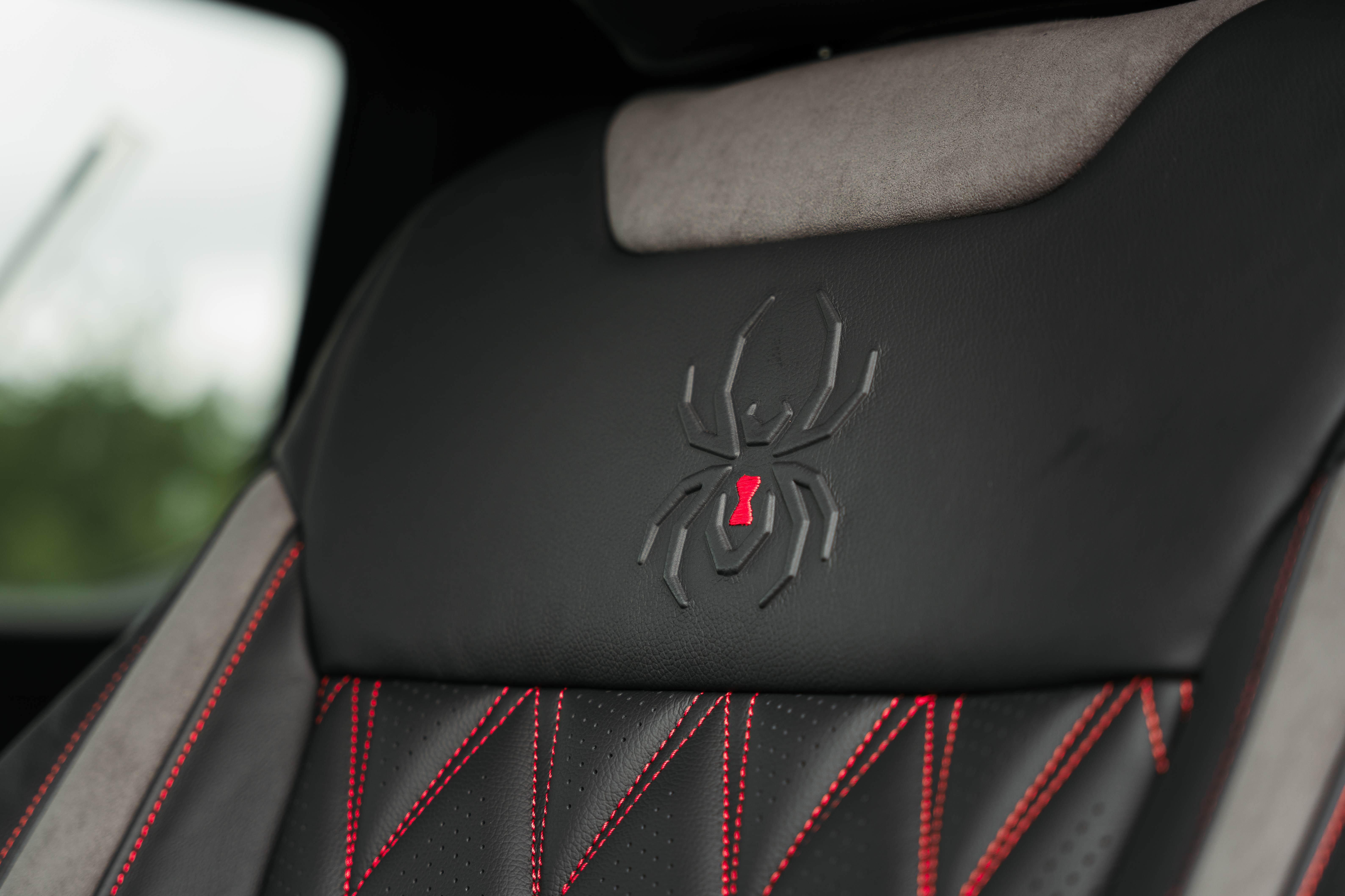 red diamond pattern stitched perforated leather upholstery and black widow spider embossed headrest on the seats of a black widow lifted truck