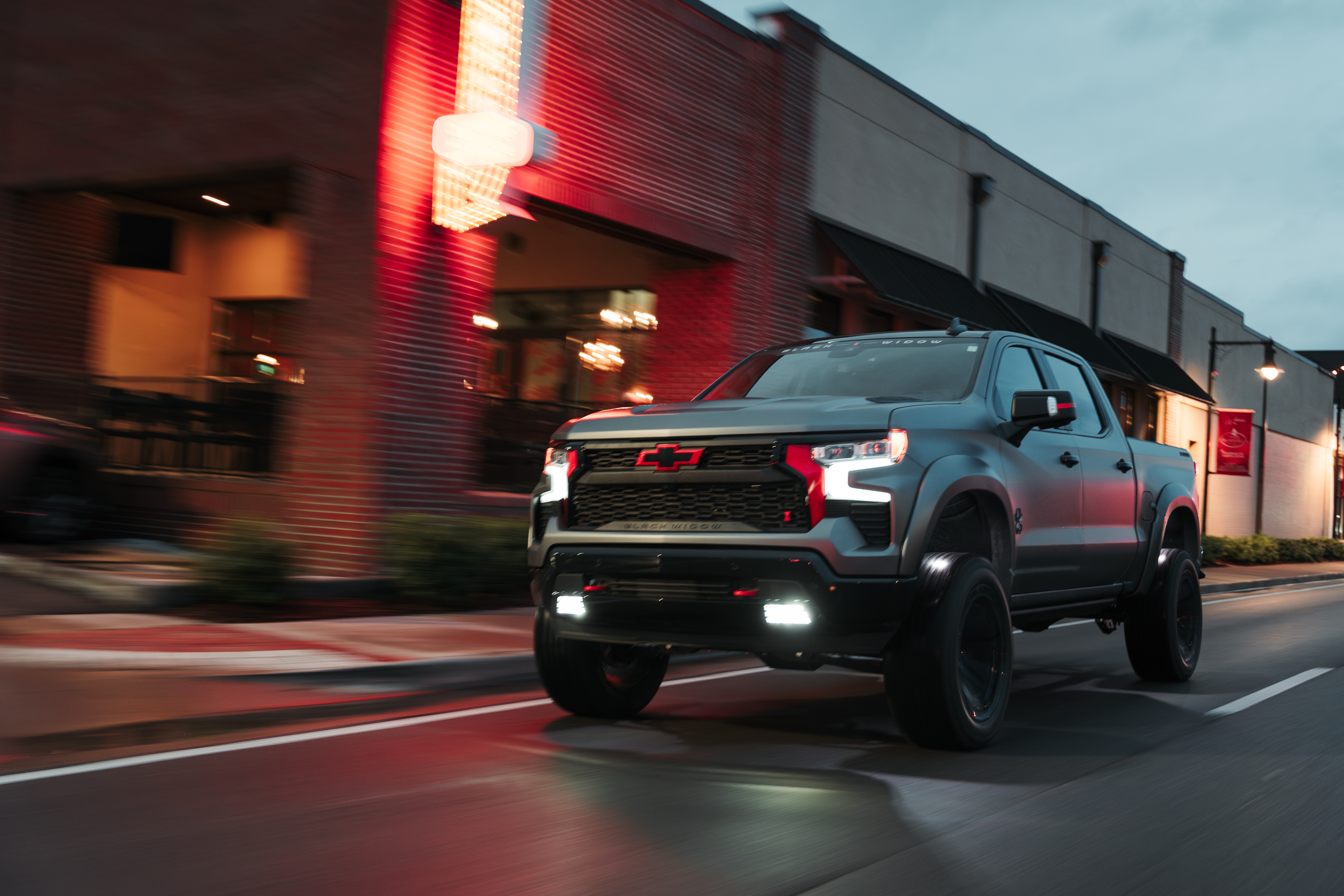 Matte Grey paint on a lifted black widow truck. Chevrolet silverado 1500 driving down a street in a small town.