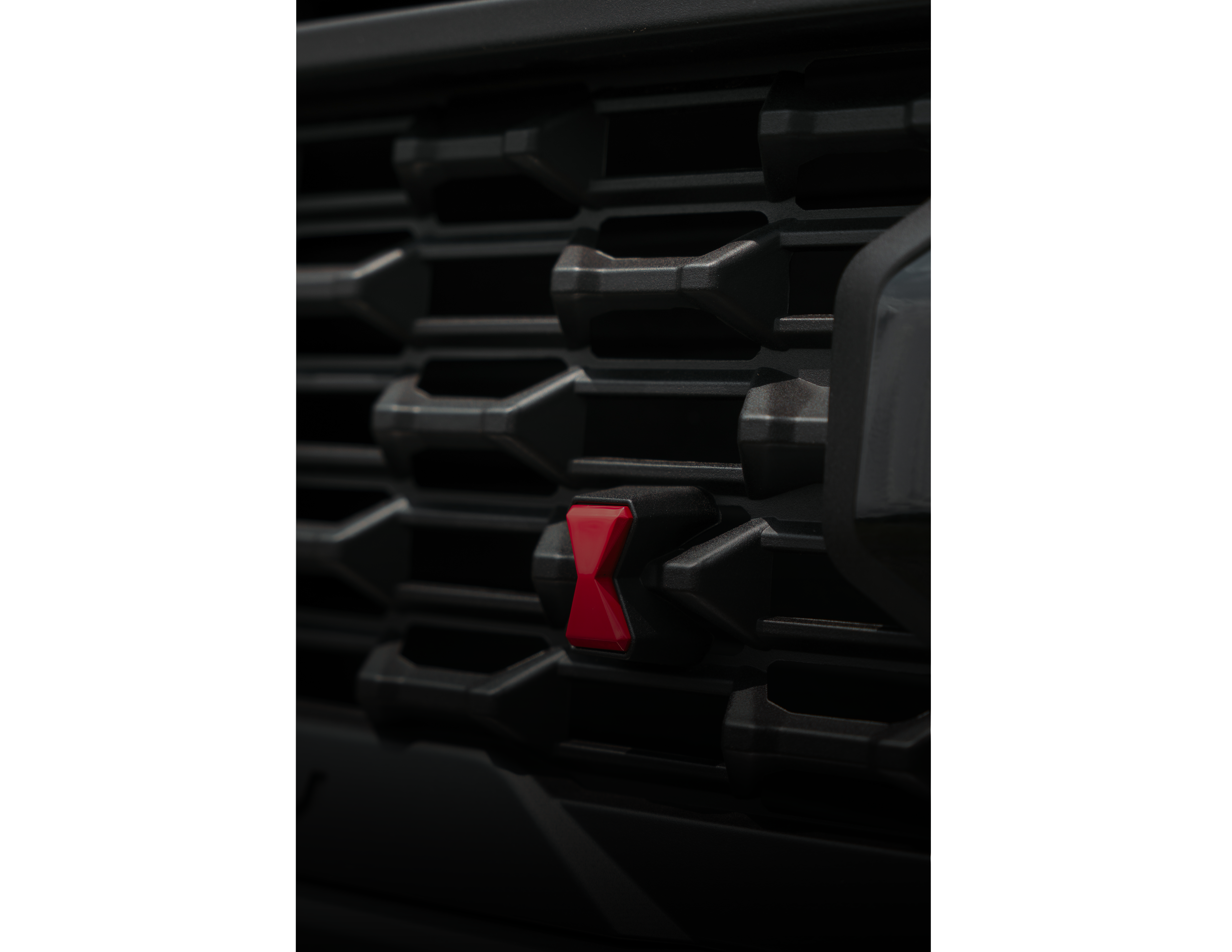 close up shot of the custom grille texture of a black widow lifted truck with a red spider accent and black powder coated grate