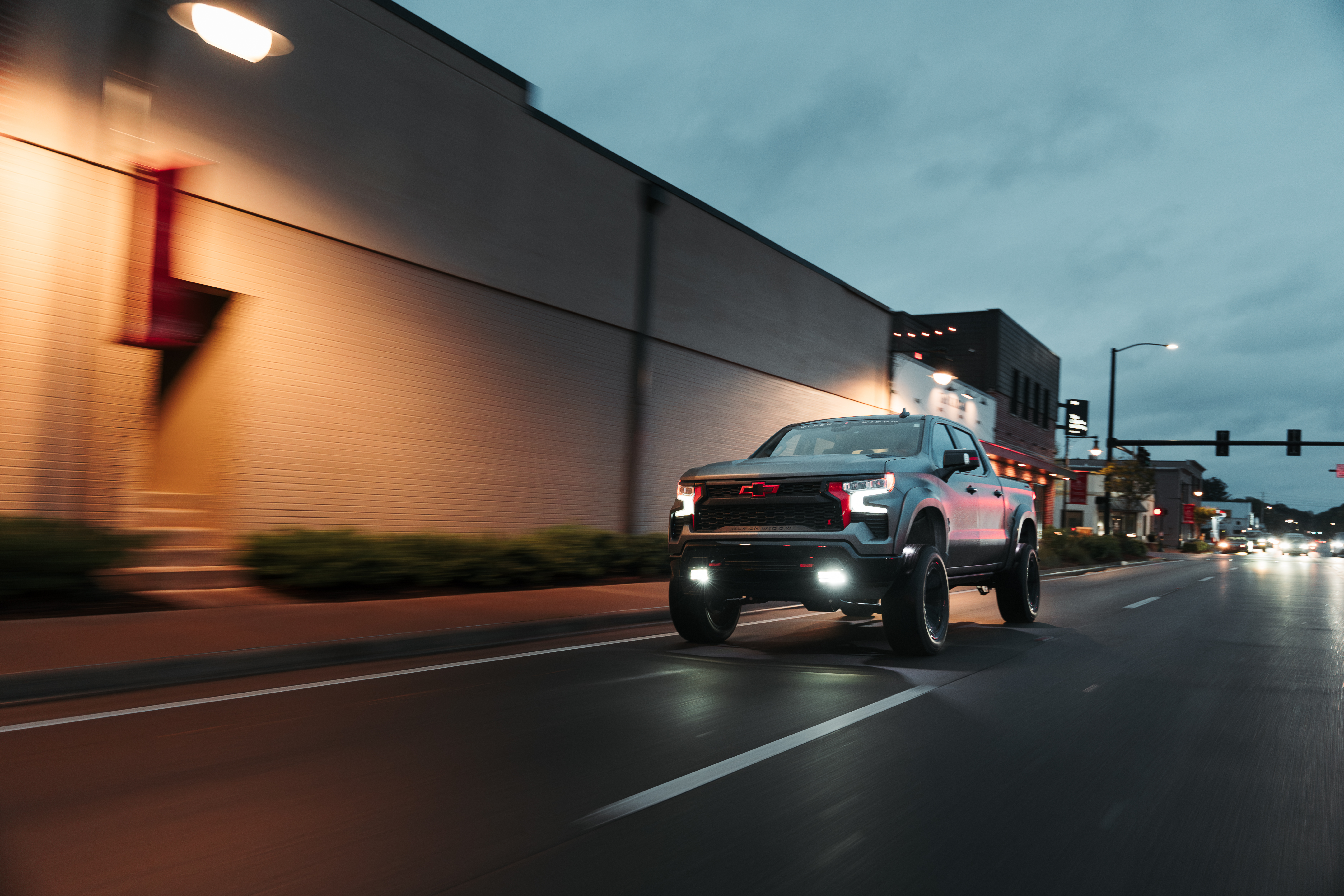 Matte Grey paint on a lifted black widow truck. Chevrolet silverado 1500 driving down a street in a small town.