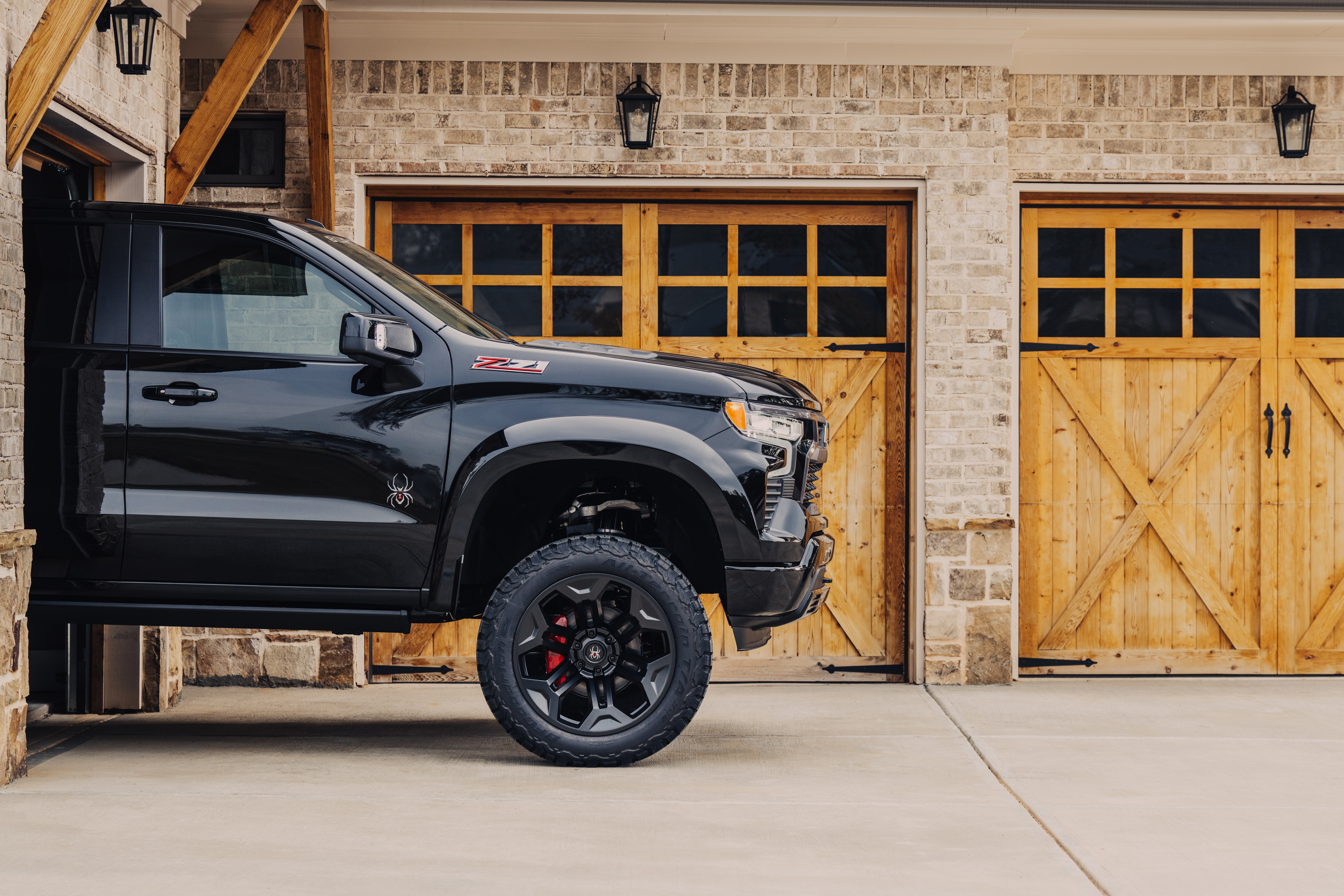 close up view of the black widow lifted truck. custom black wheels on a chevrolet silverado 1500 with a red caliper cover and black widow spider logo