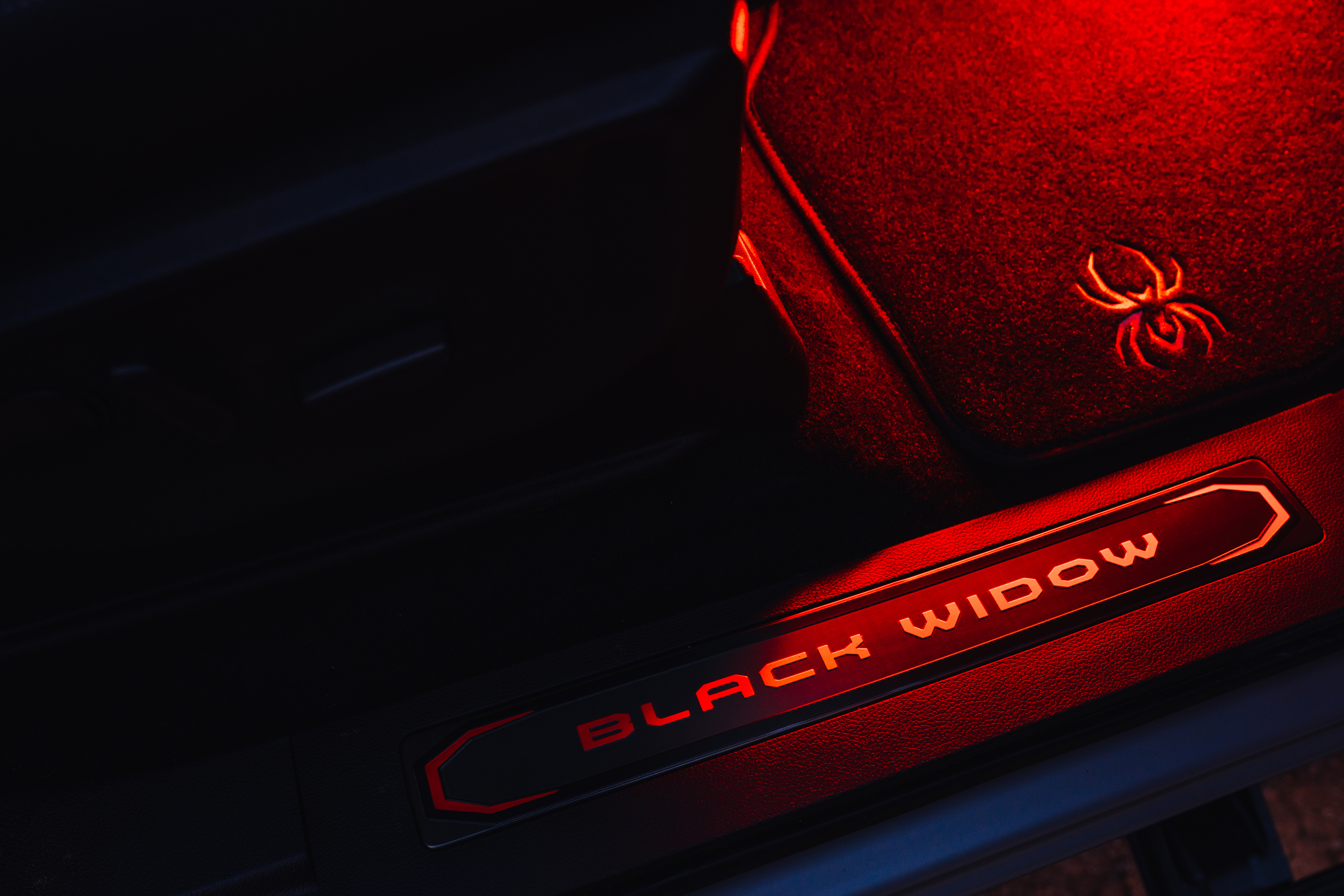 Red LED Interior Lighting package of a Black Widow truck with spyder logo embossed door sill and embroidered floor mats