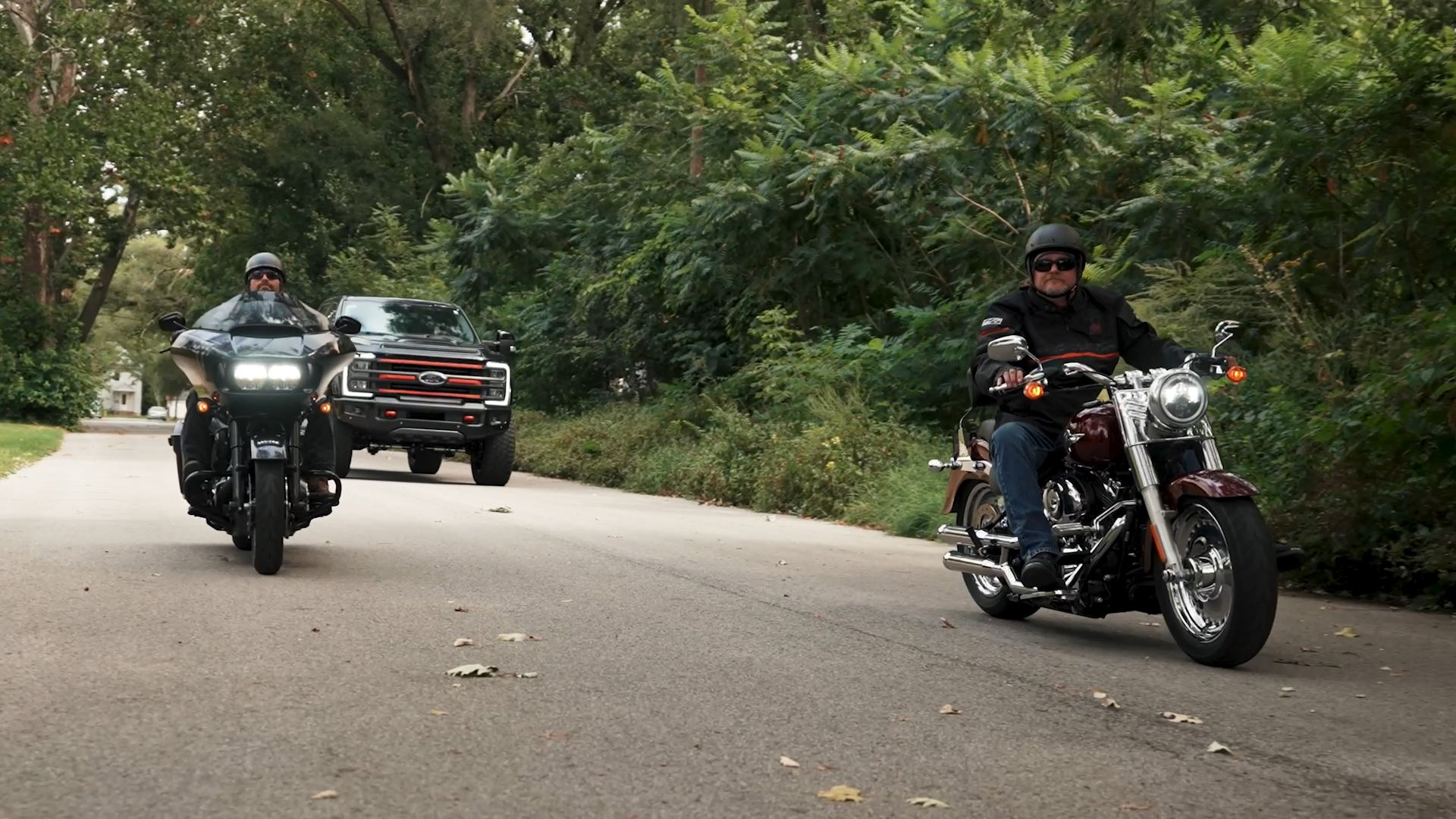 two Harley-Davidson motorcycles riding in front of the black ford superduty lifted Harley-Davidson truck