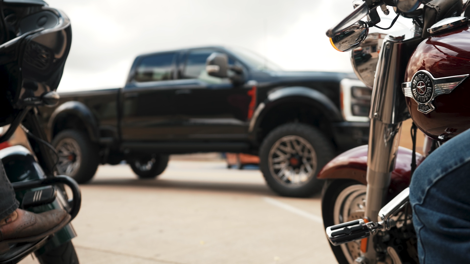 two harley davidson motorcycles in front of a harley davidson black lifted truck