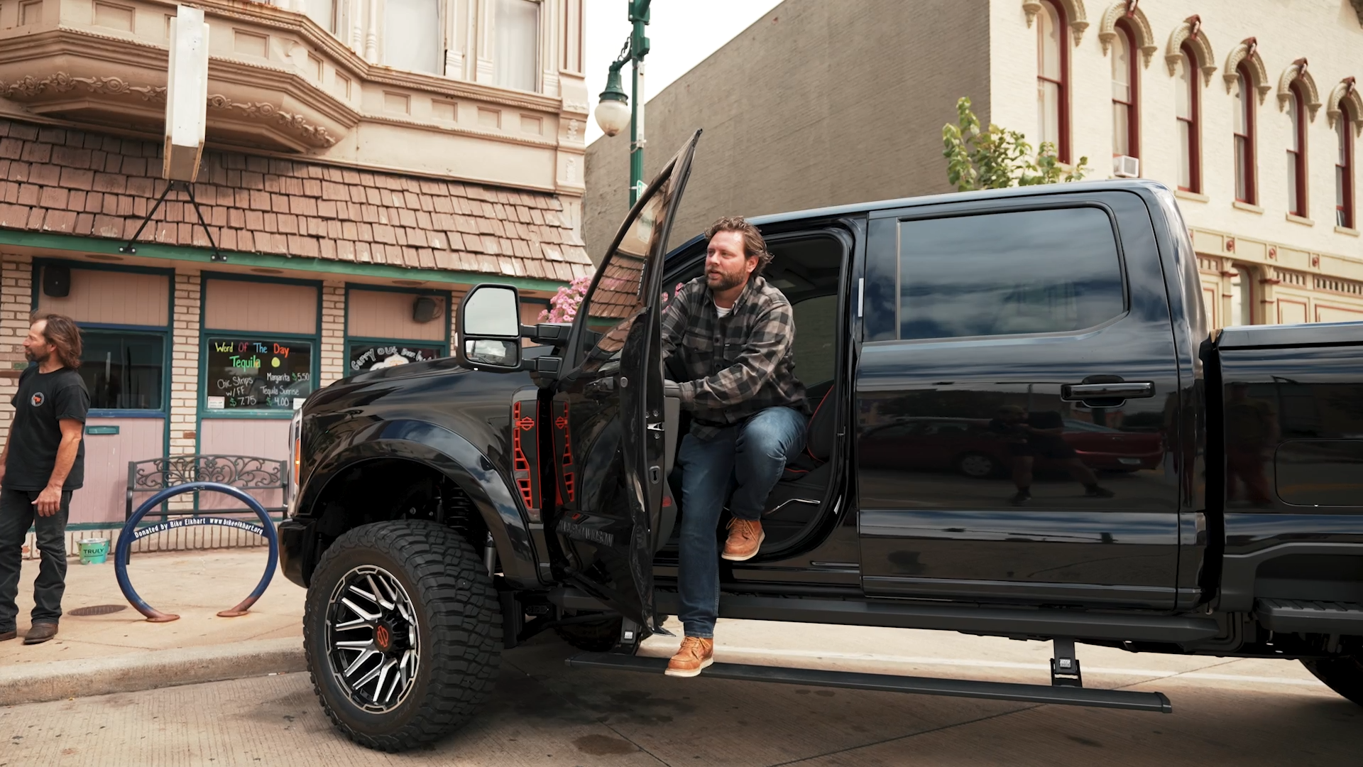 man exiting a black lifted Harley-Davidson truck with foot on power running board
