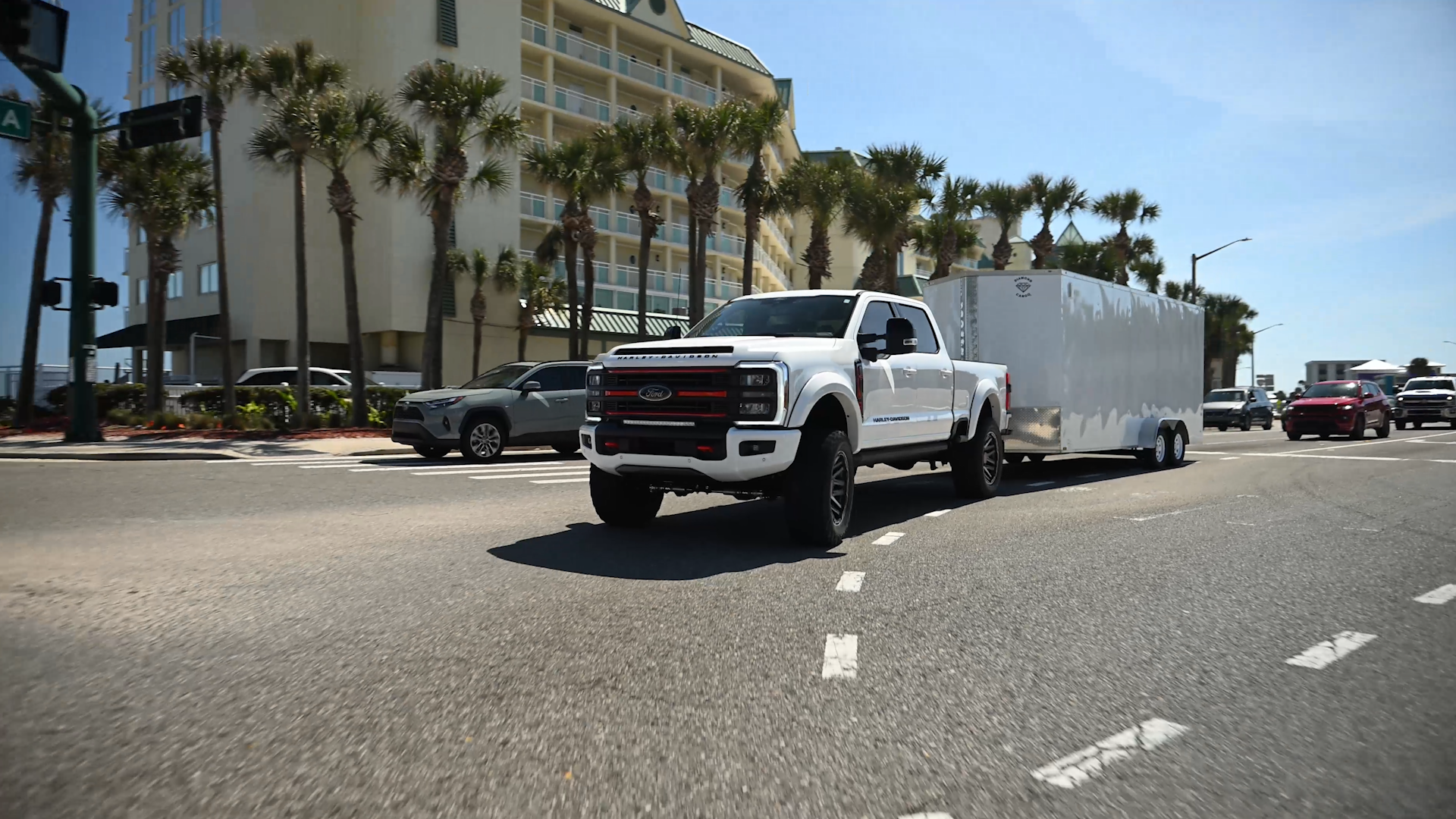 white ford superduty lifted Harley-Davidson truck towing a covered motorcycle trailer
