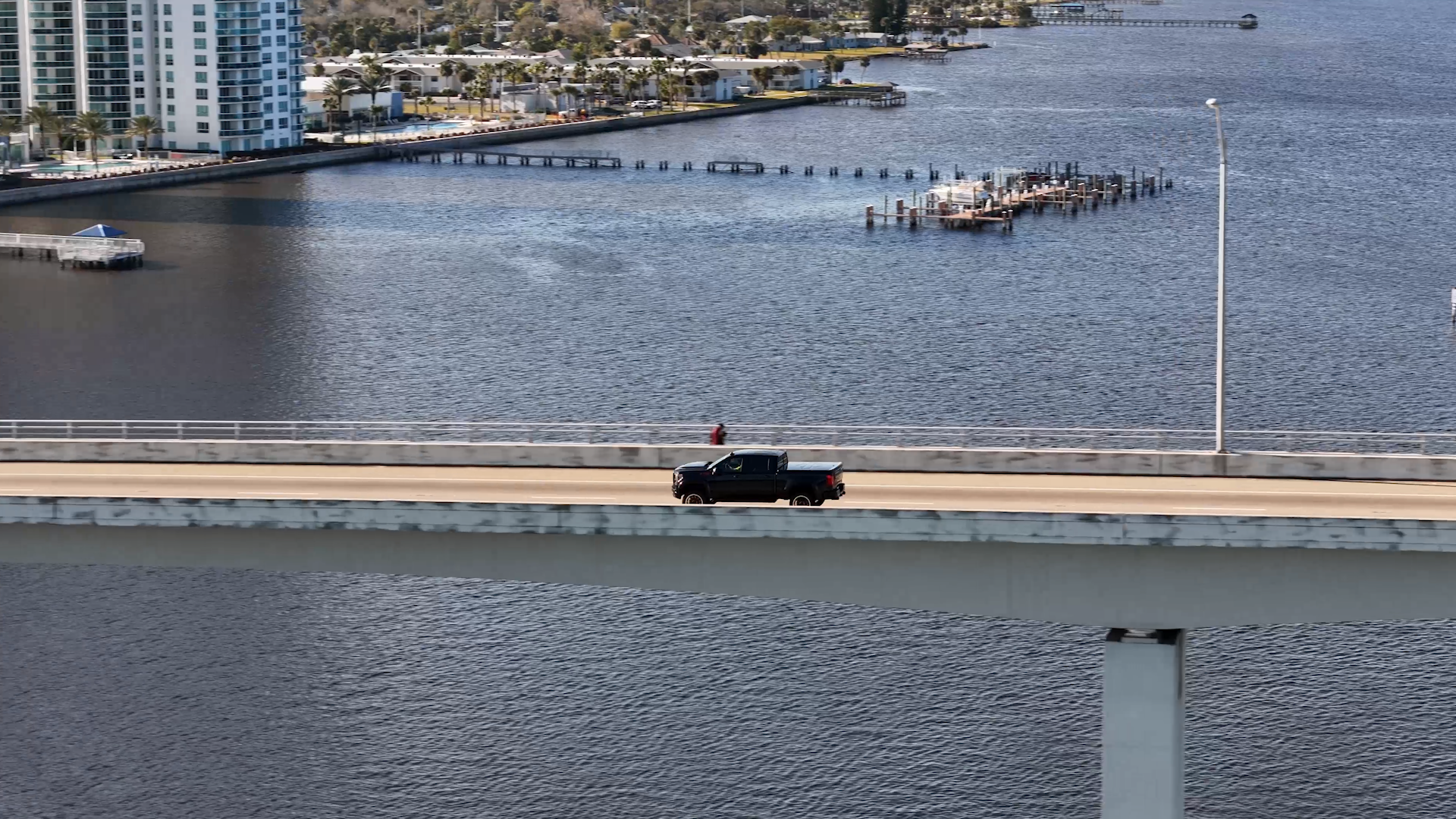 black lifted Harley-Davidson truck driving on a bridge over a harbor