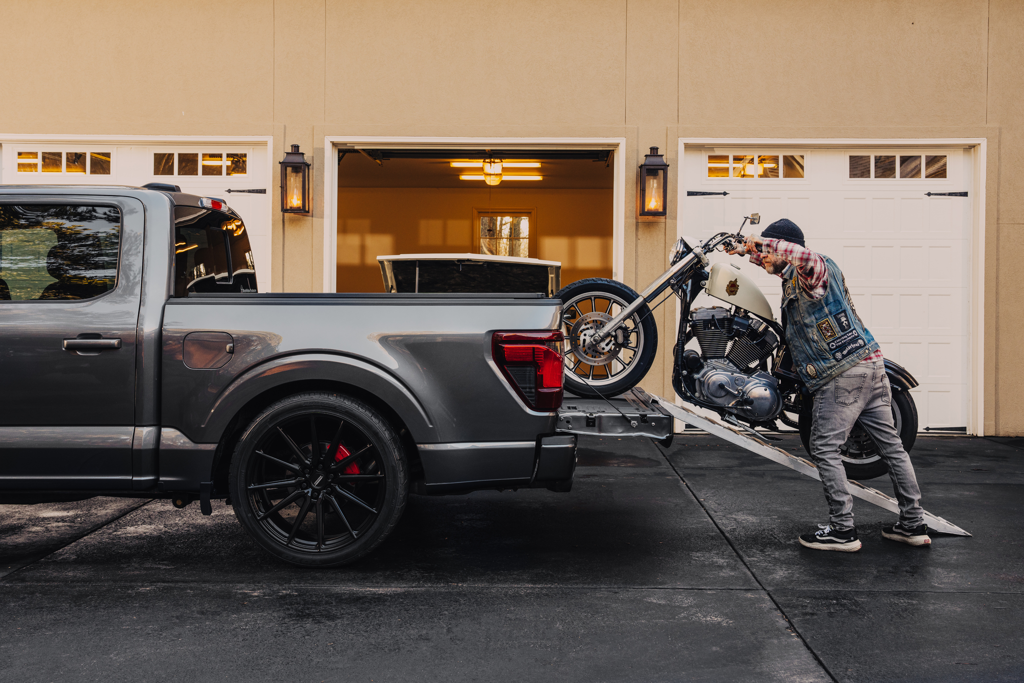 Man loading his motorcycle into the truck bed of a lowered Black Widow F-150
