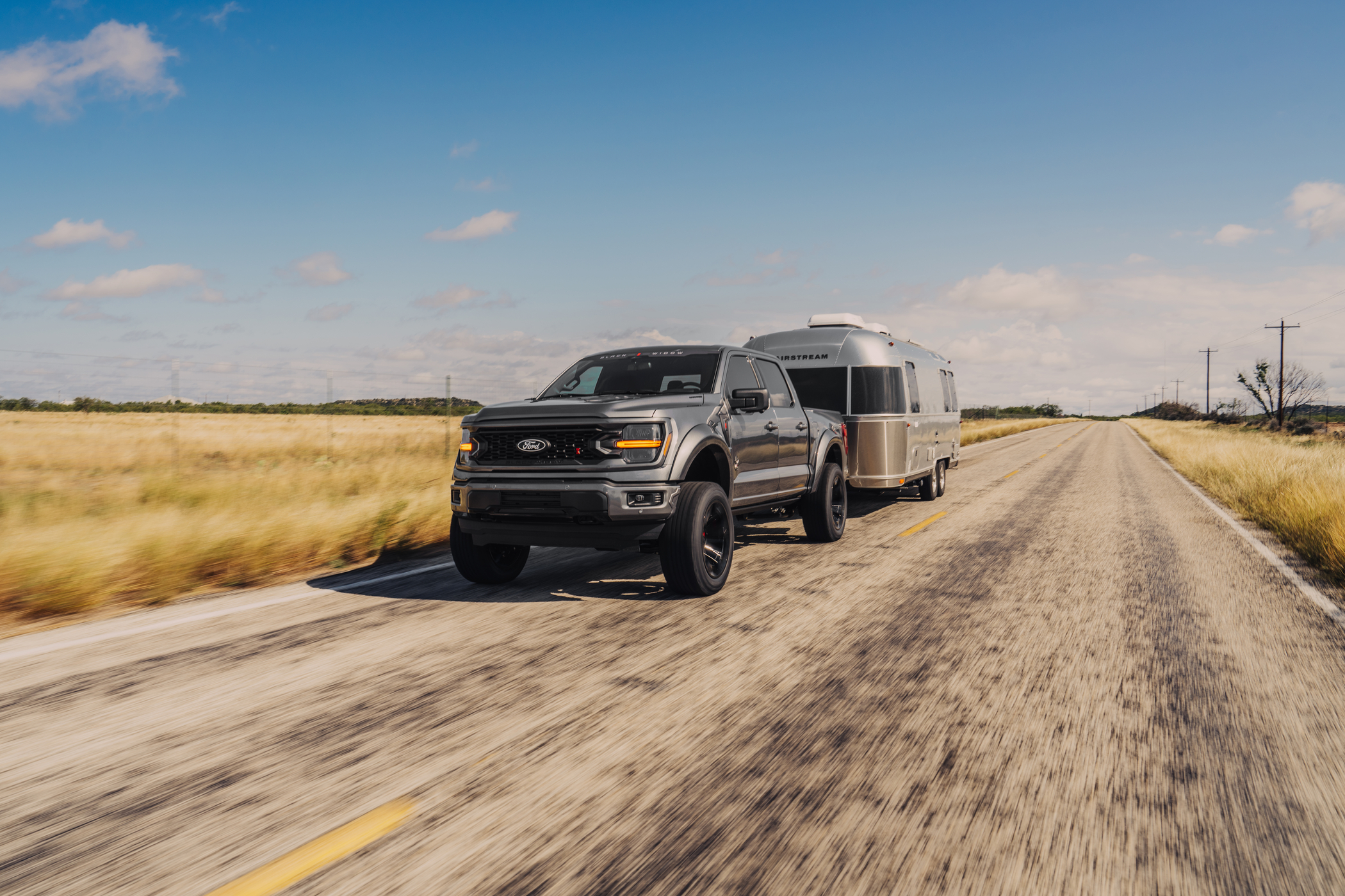 Black Widow F-150 truck towing Airstream camper trailer.