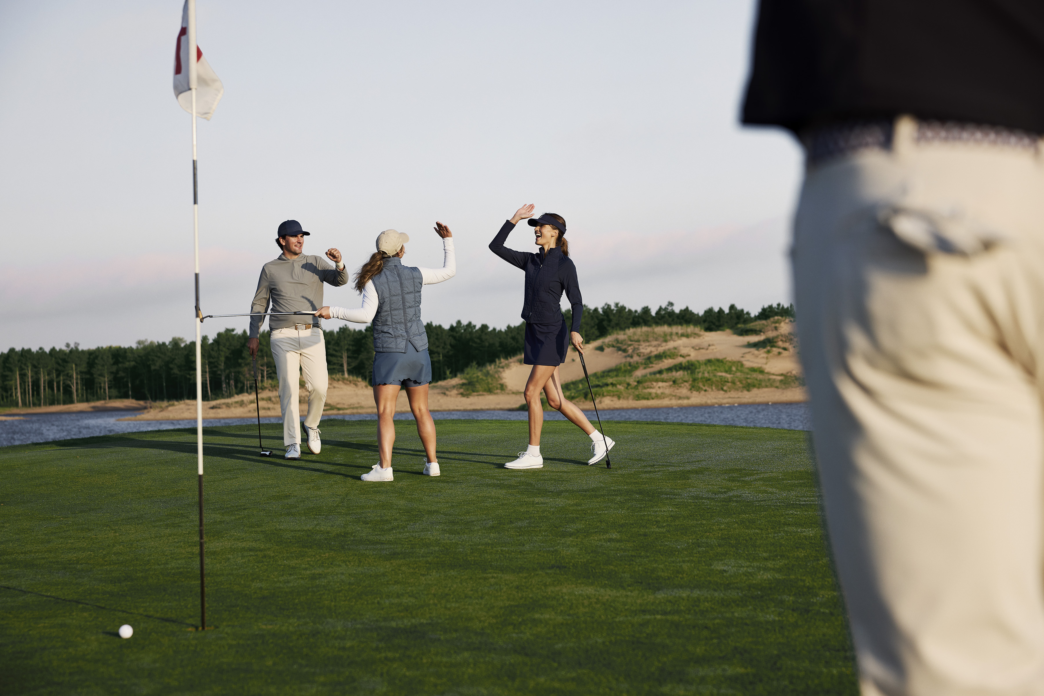 Golf ball and golf club in a beautiful golf course at sunset background. Collection of golf equipment resting on green grass with green background