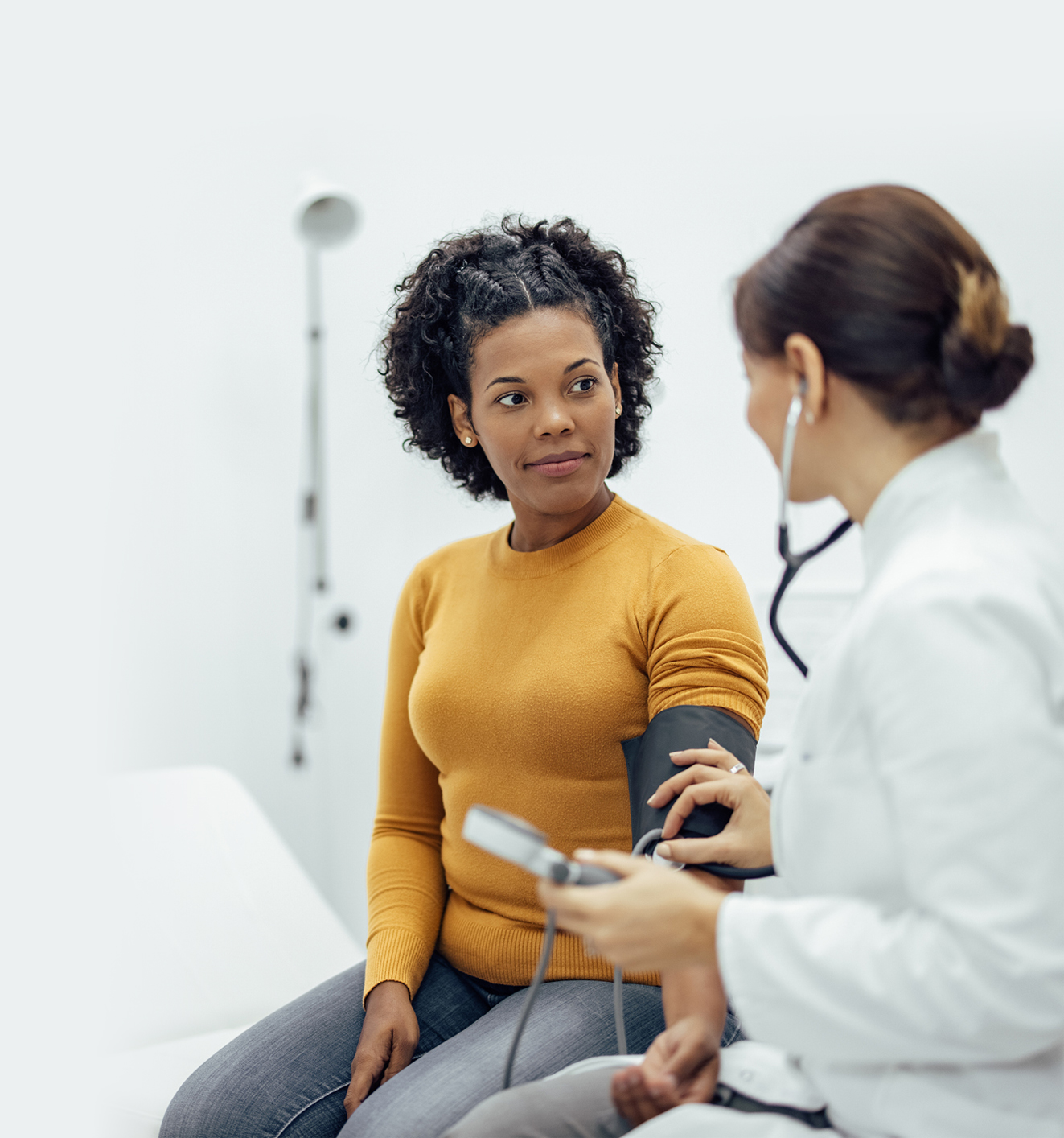 Doctor measuring blood pressure to a smiling woman as a part of a medical exam.