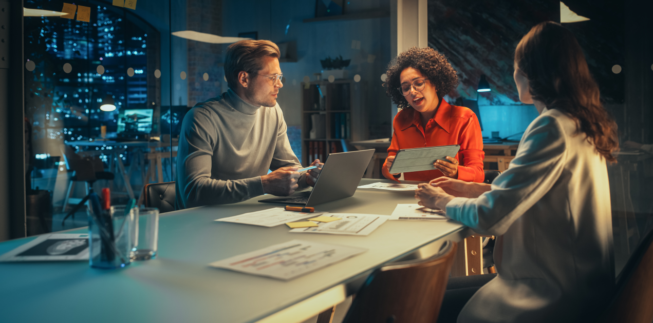 3 businesspeople around a table at night