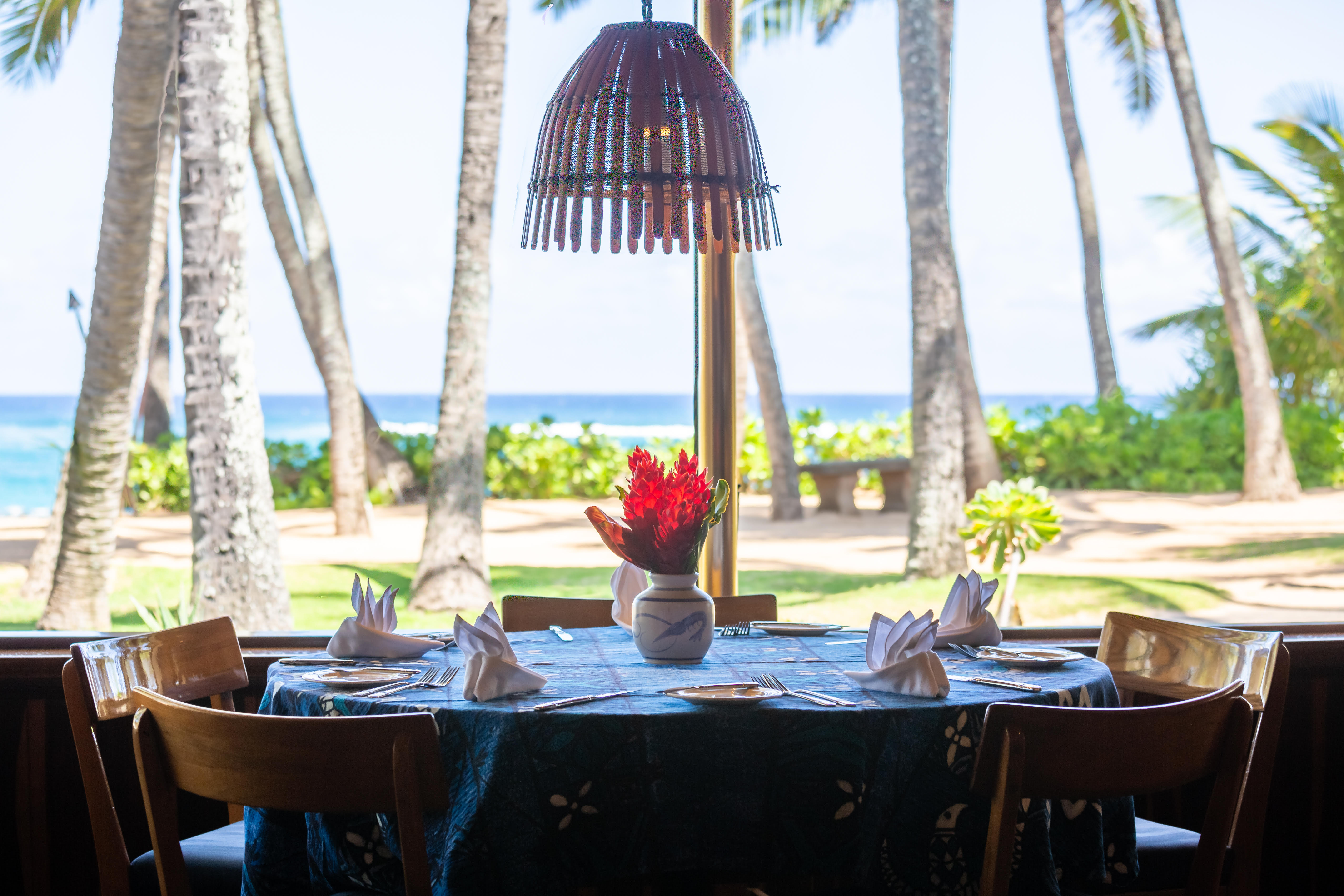 Table set for six at an outdoor restaurant, with a view of the ocean beyond