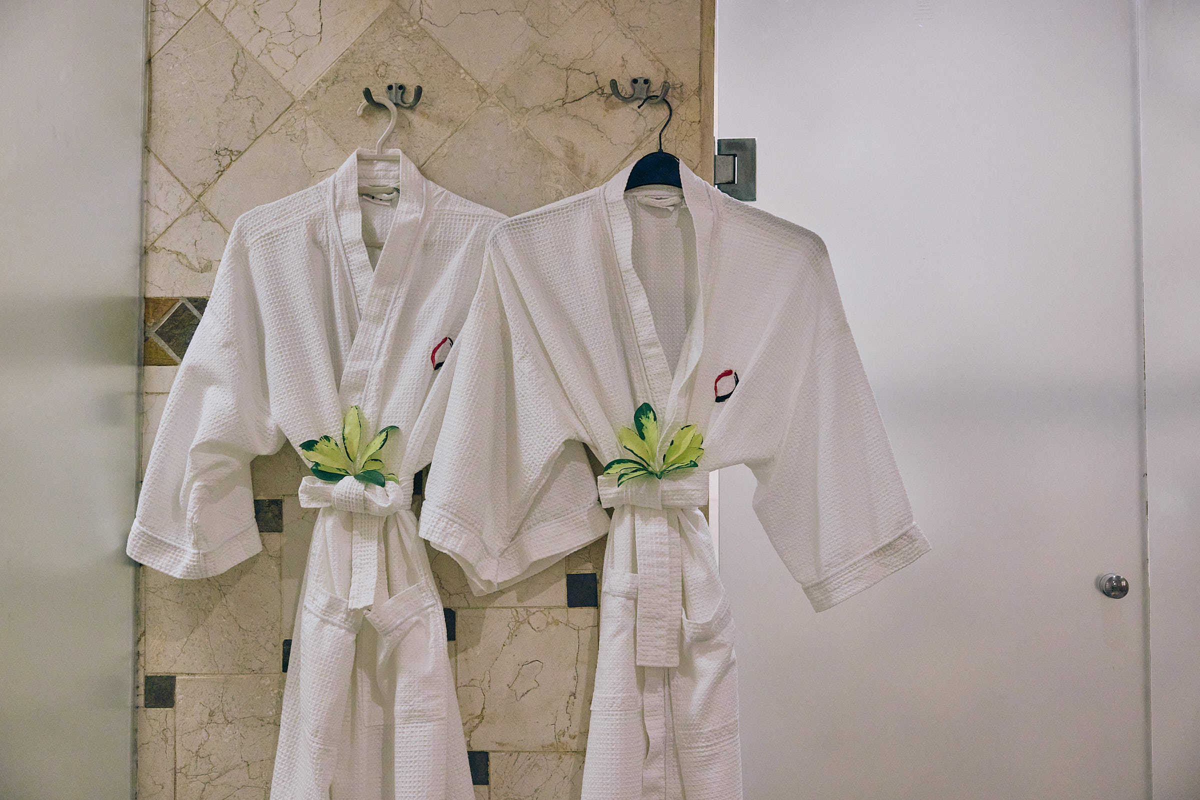 Two white robes hanging in a hotel room