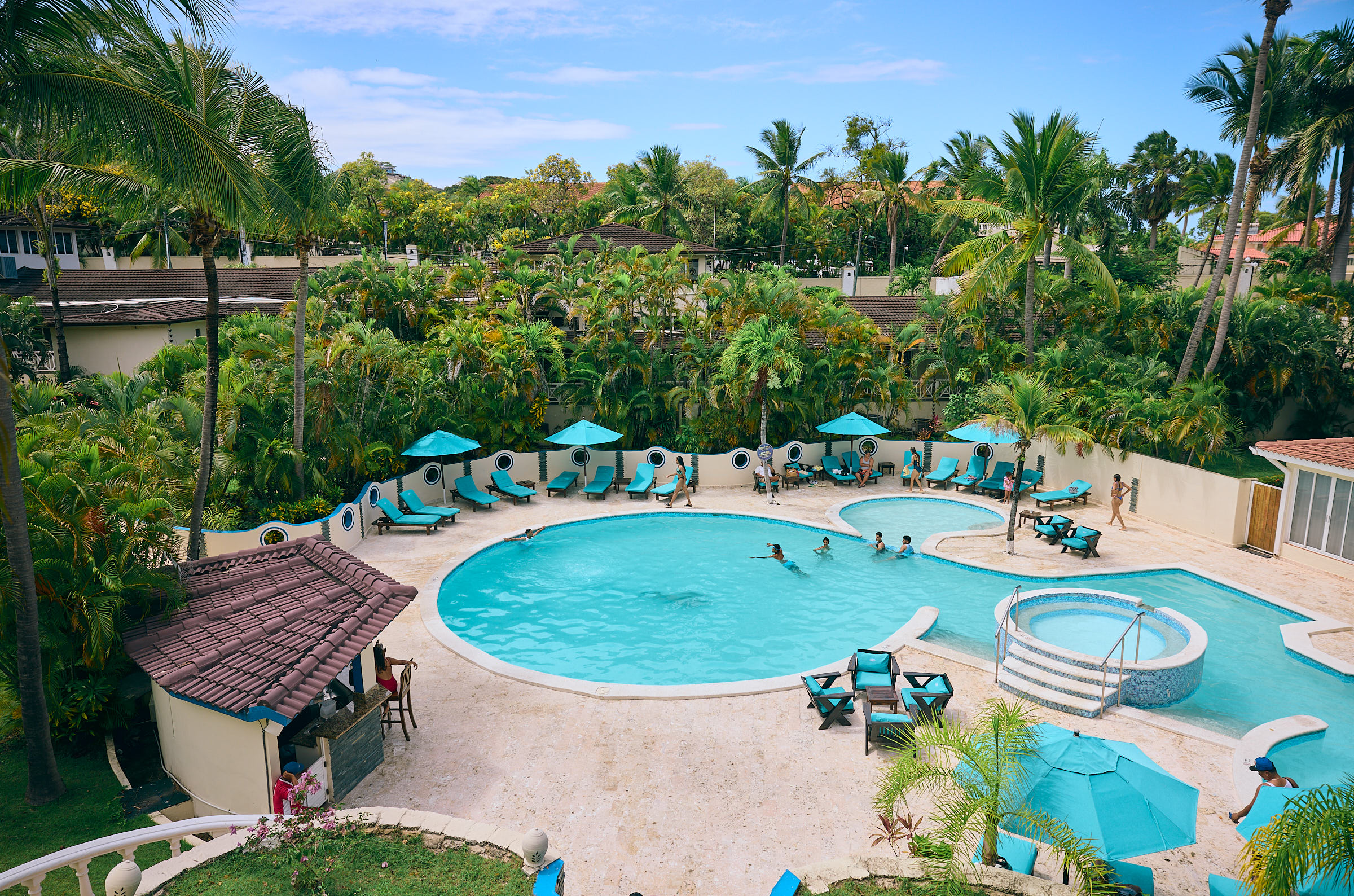 Curvy outdoor pool surrounded by blue lounge chairs and umbrellas