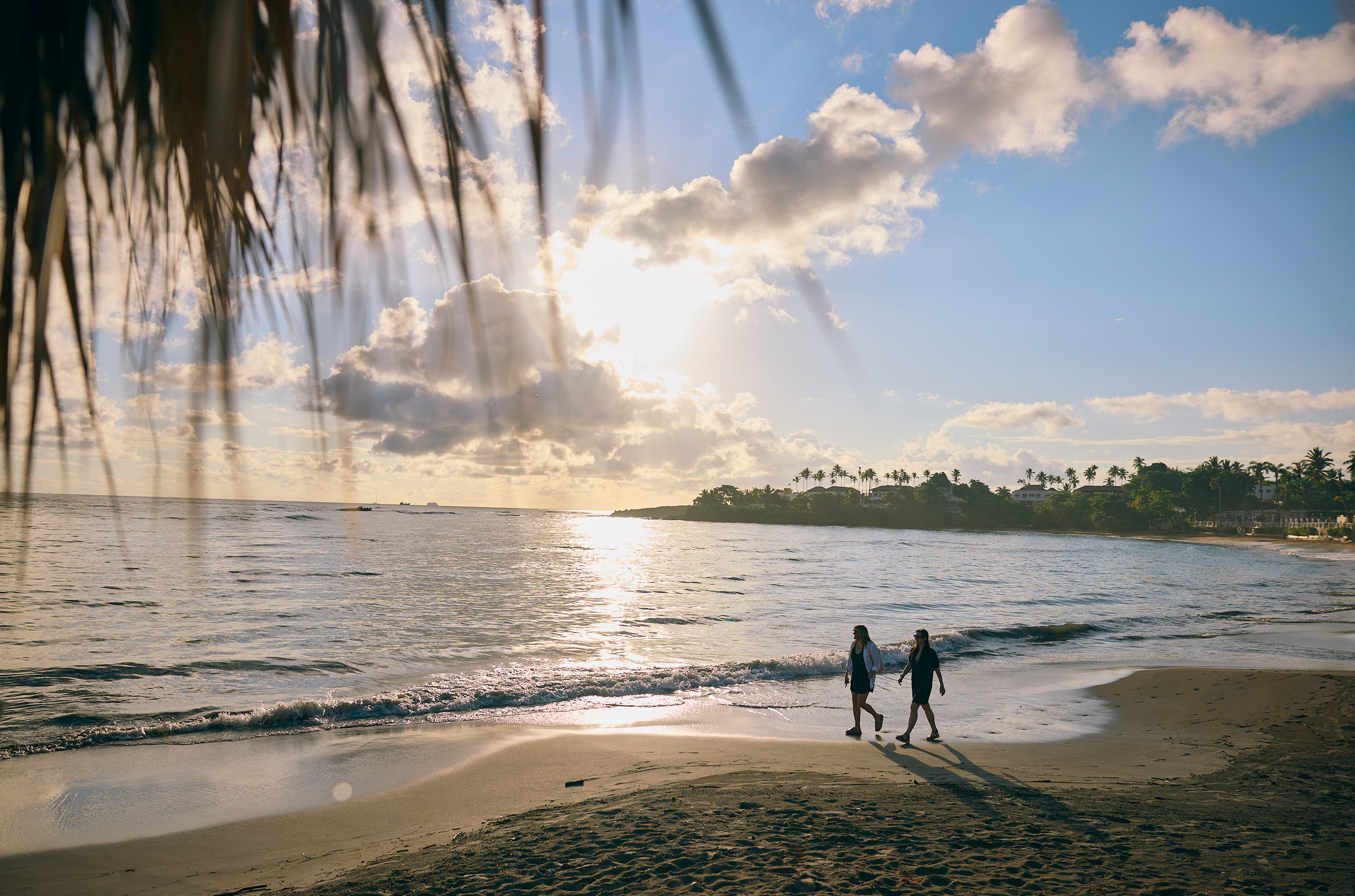 Two people walking along the beach at sunset