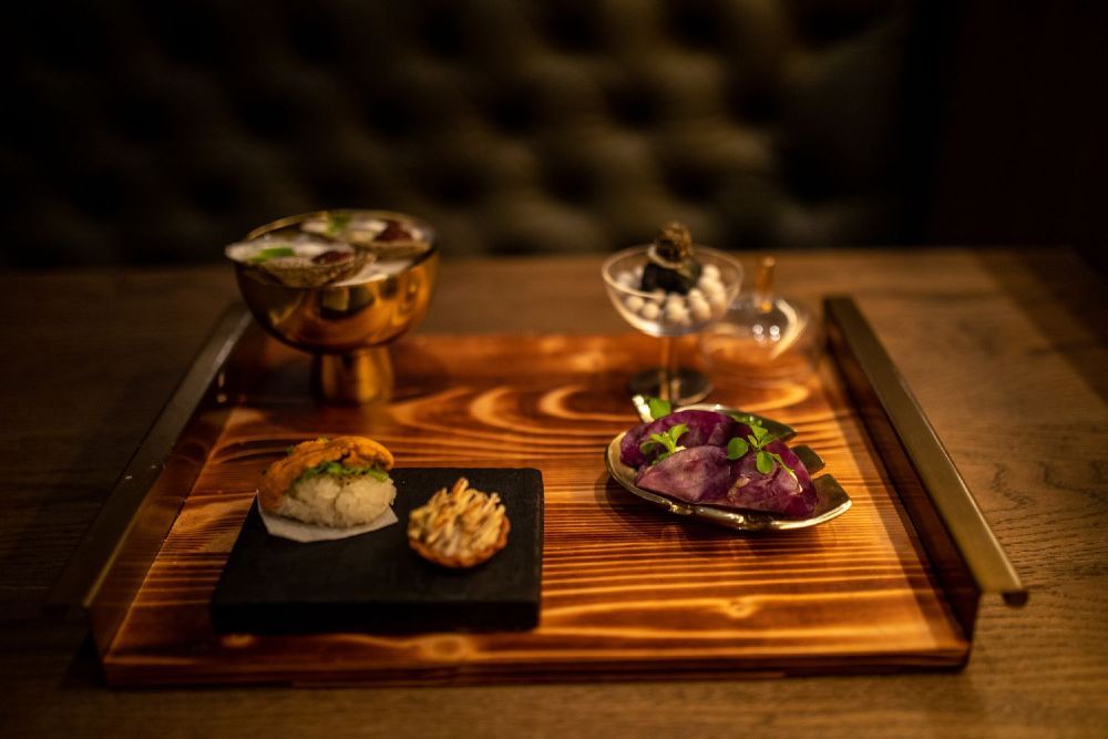 Wood tray with small, unique culinary dishes on it