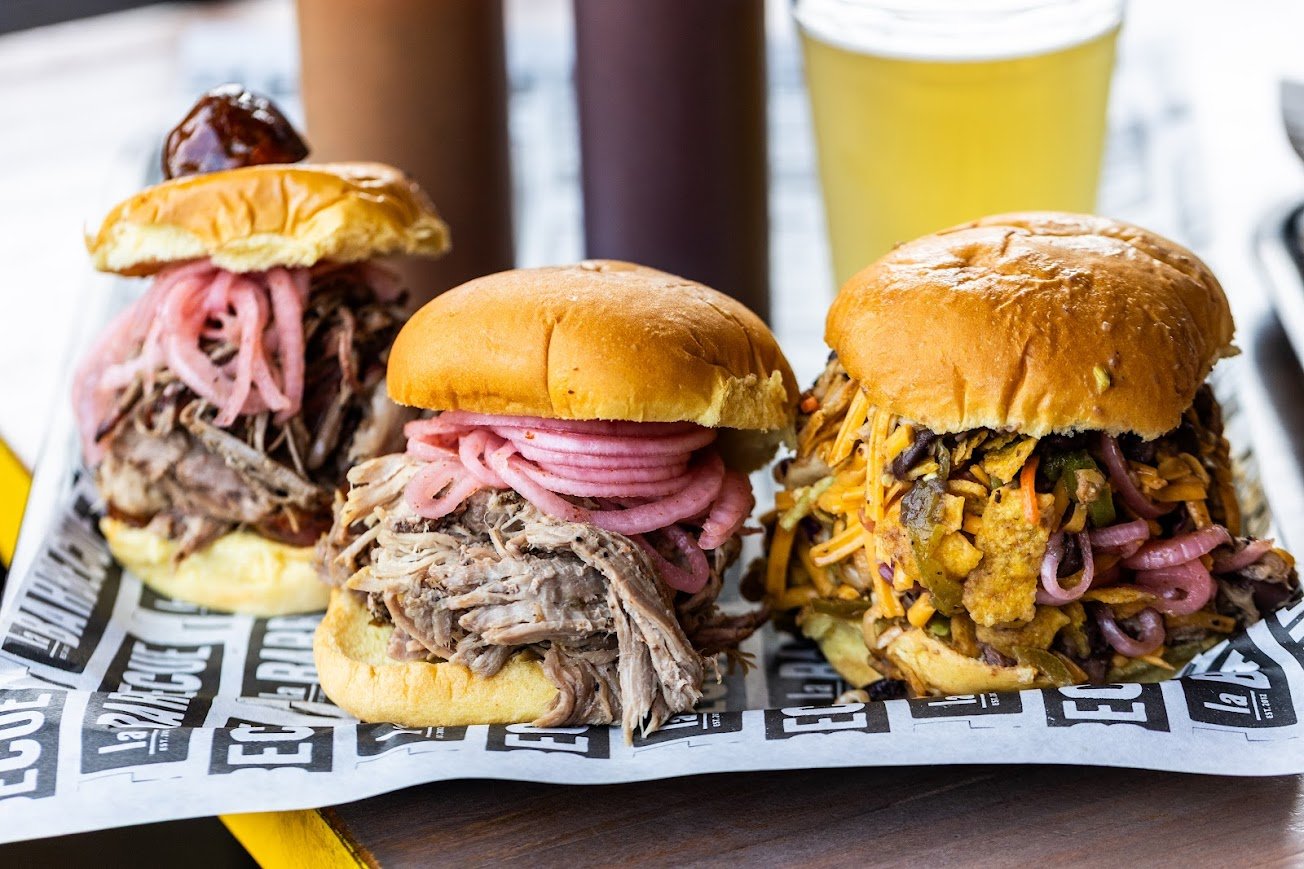 Three large, smoked meat sandwiches on a tray
