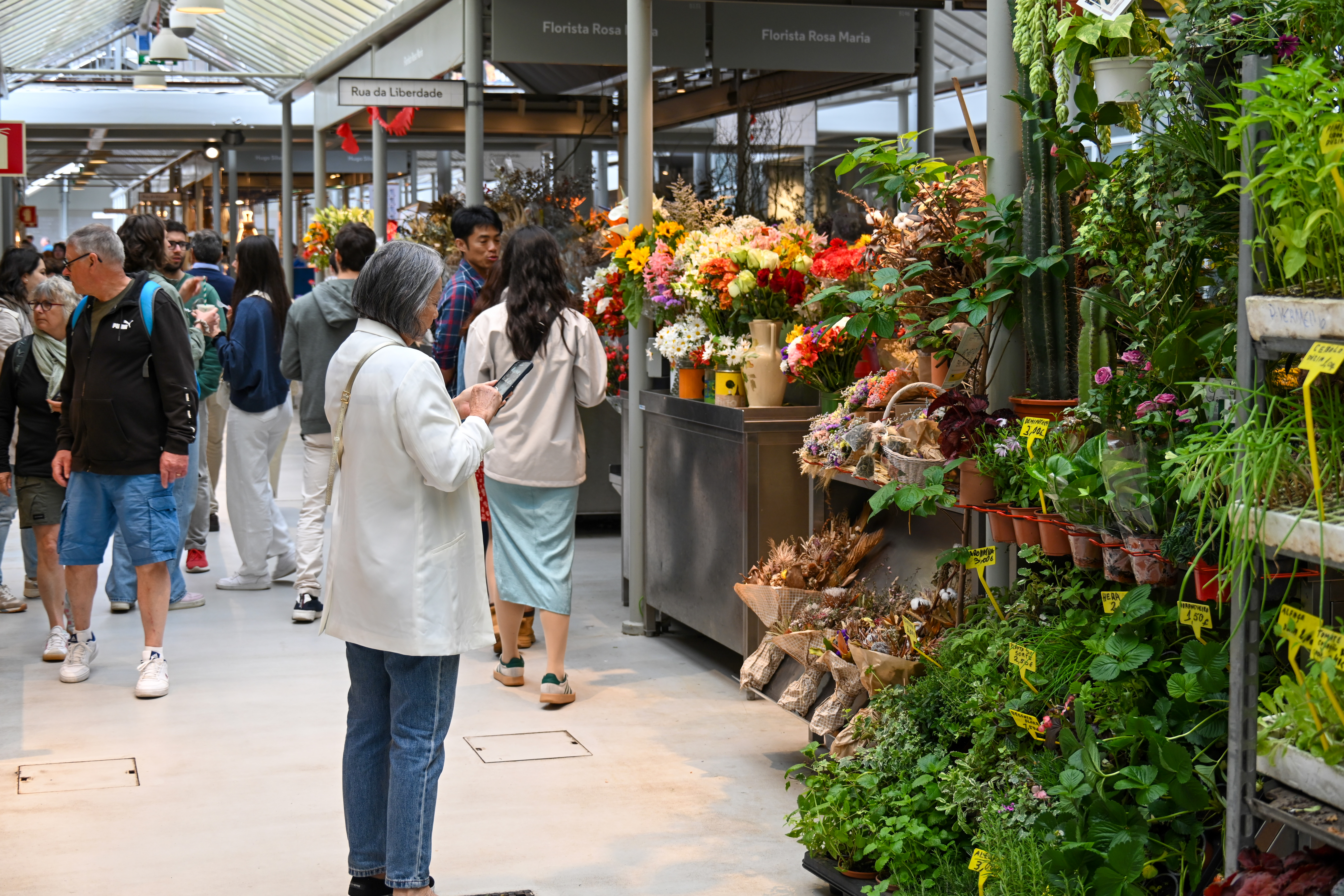 Bustling semi-outdoor market with shoppers at flower stands