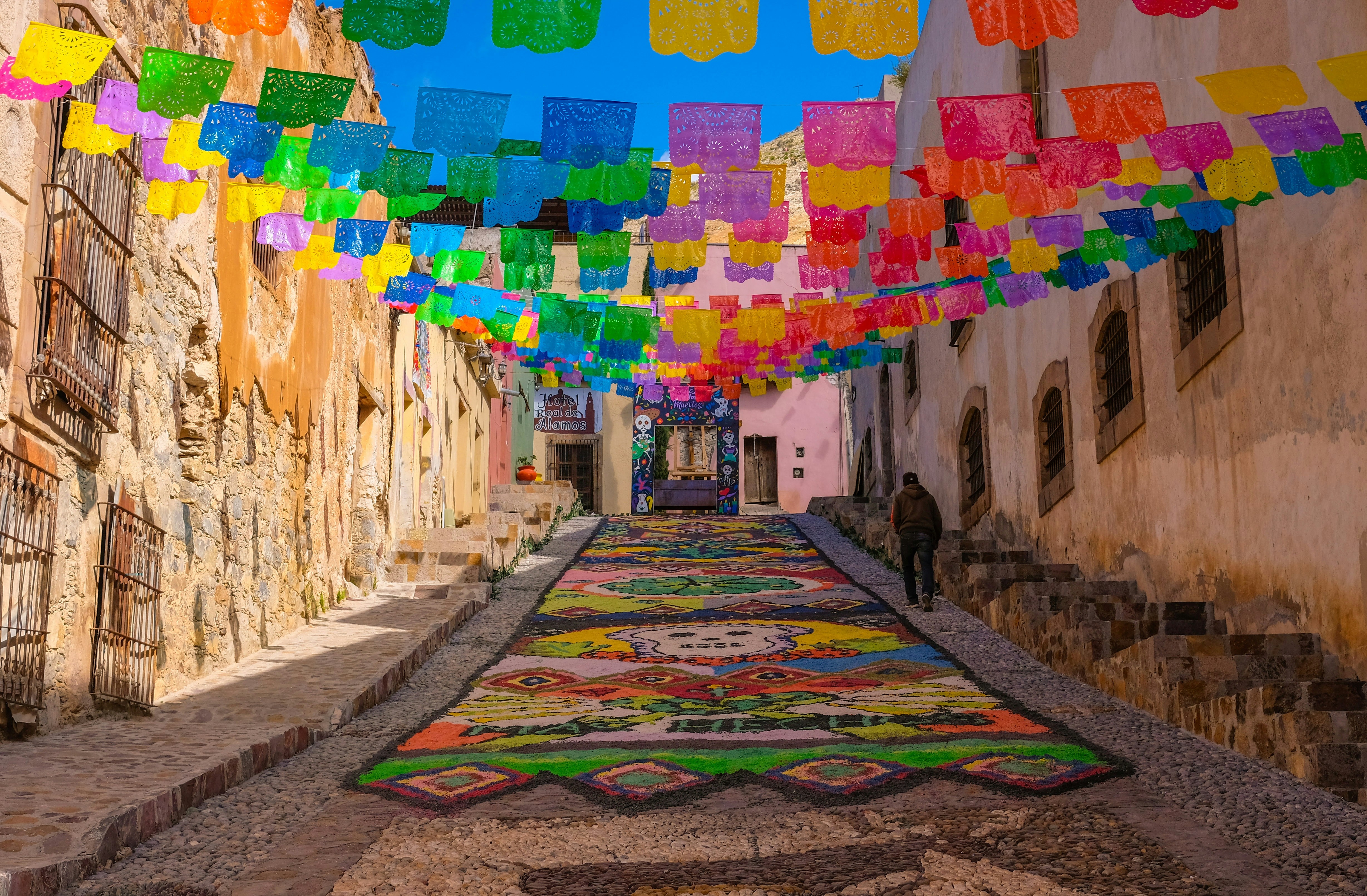 Colored paper cutouts strung in rows over an alley in Mexico