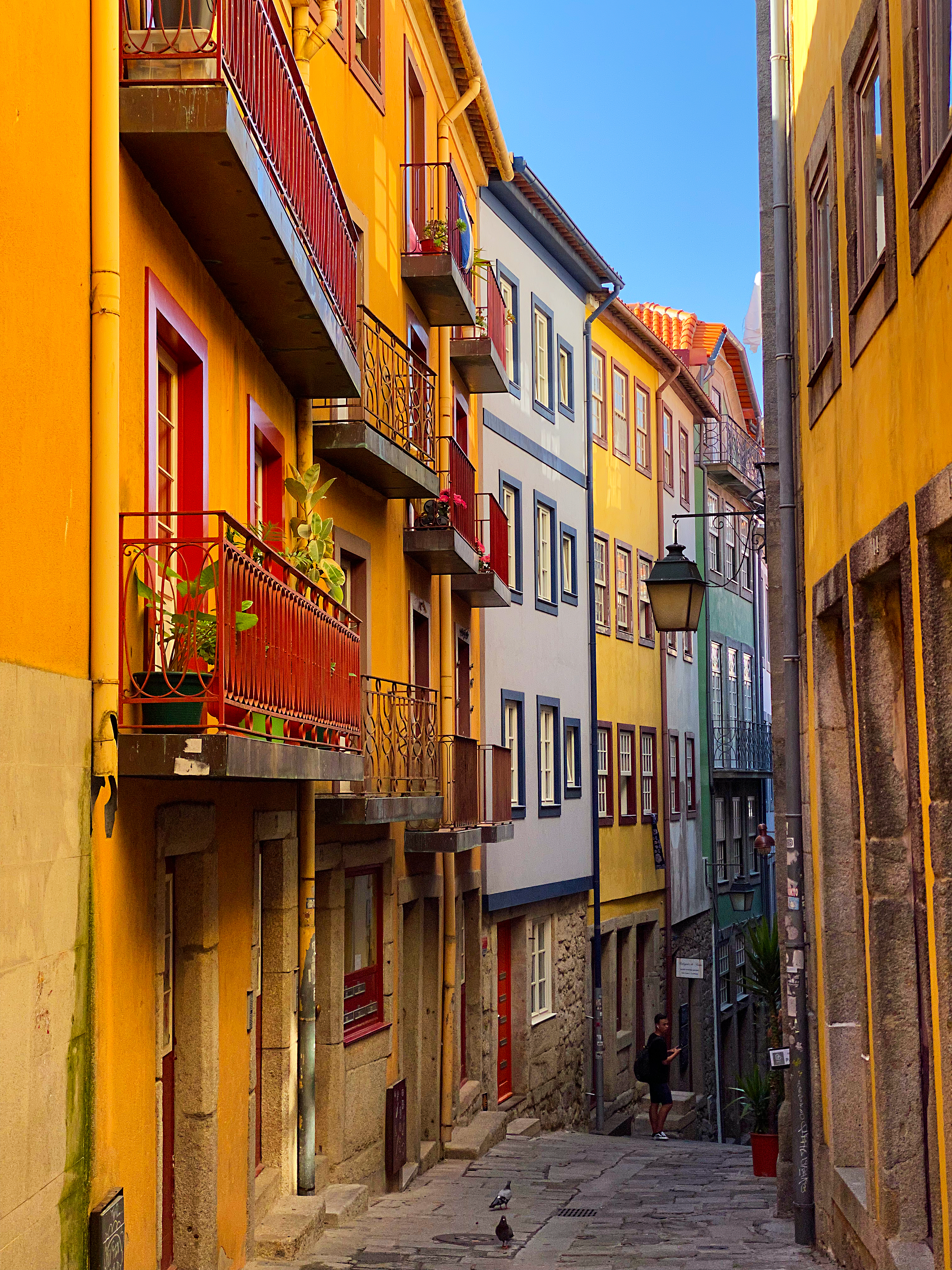 Brightly colored stucco buildings line a very narrow stone street in Portugal