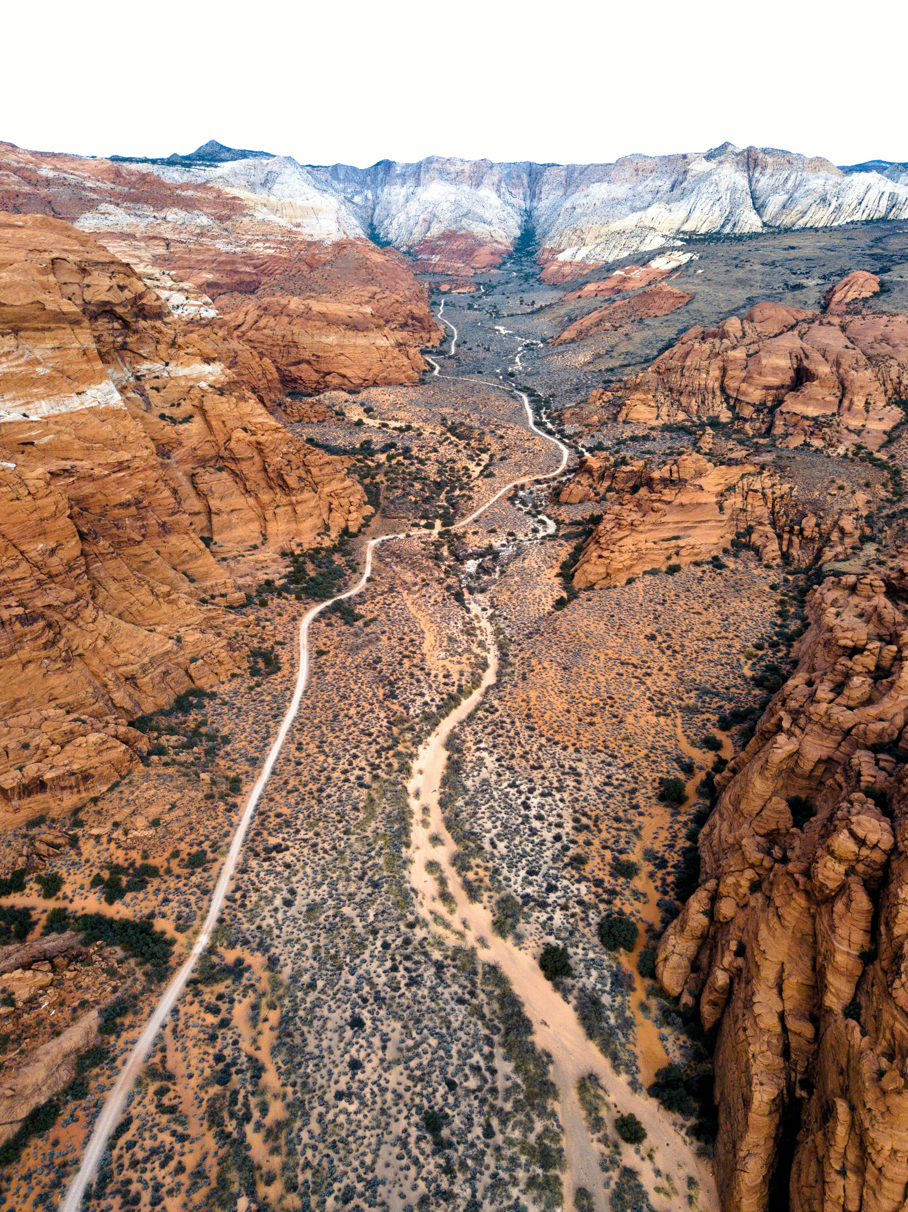 Aerial view of an orange canyon surrounded by snow-capped mountains