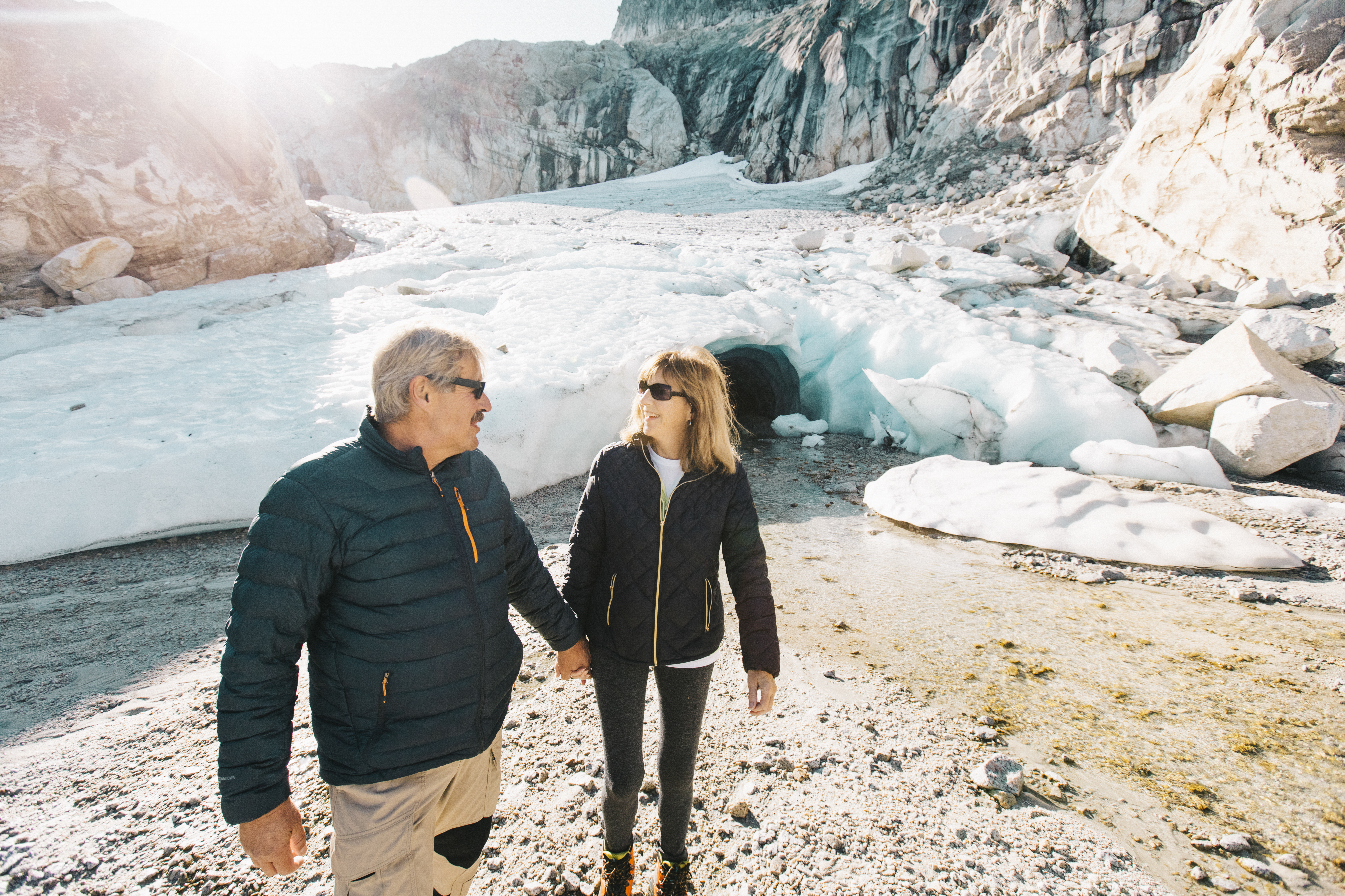 Couple in their 50s are holding hands in front of a glacier near Vancouver
