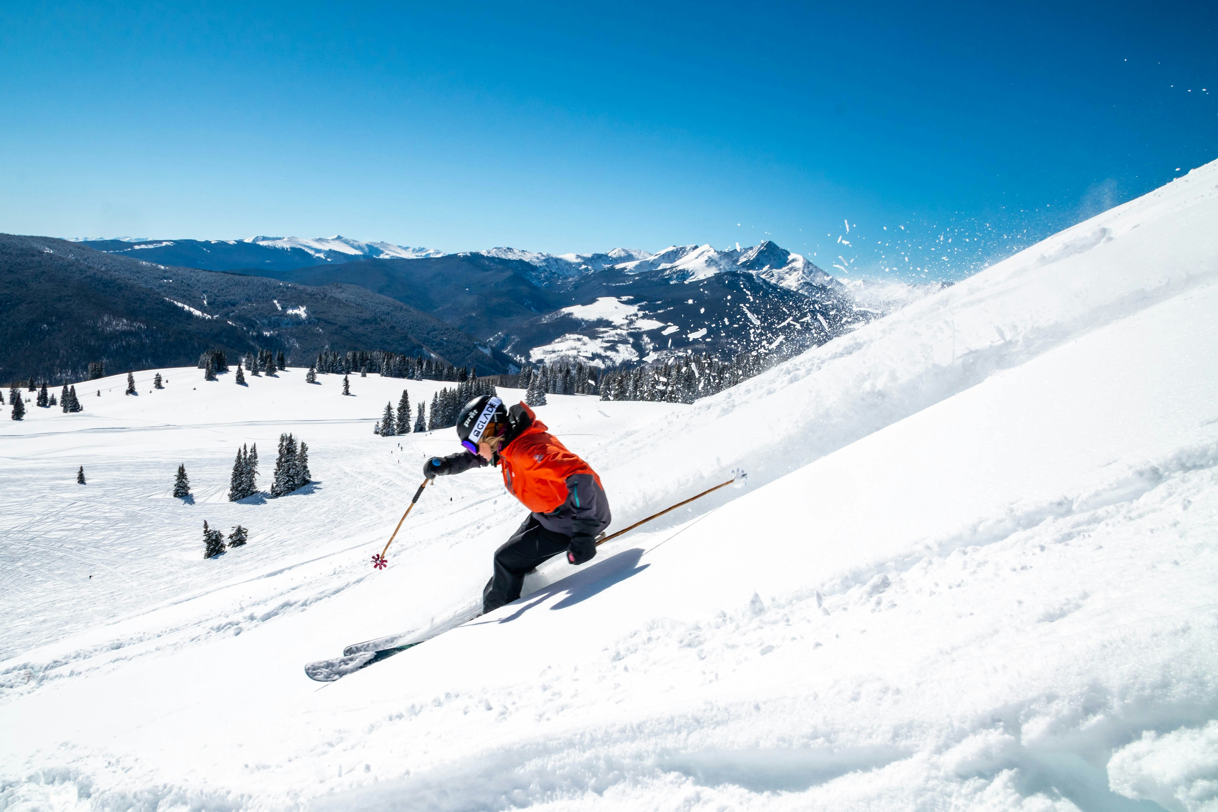 Woman in a red jacket skiing down a hill in Vail, Colorado