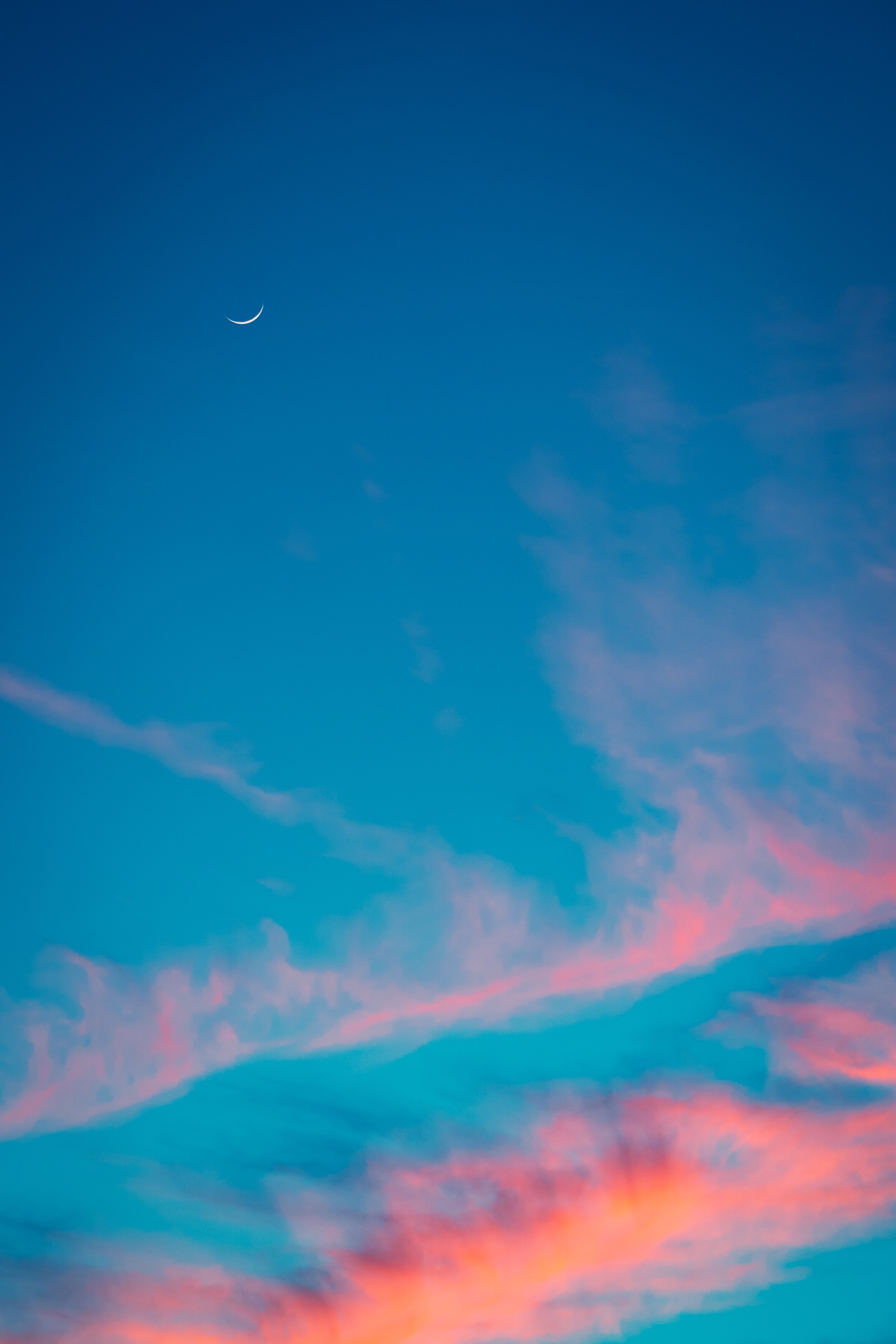 Peaceful blue sky with sunset color clouds in red, orange, and pink.