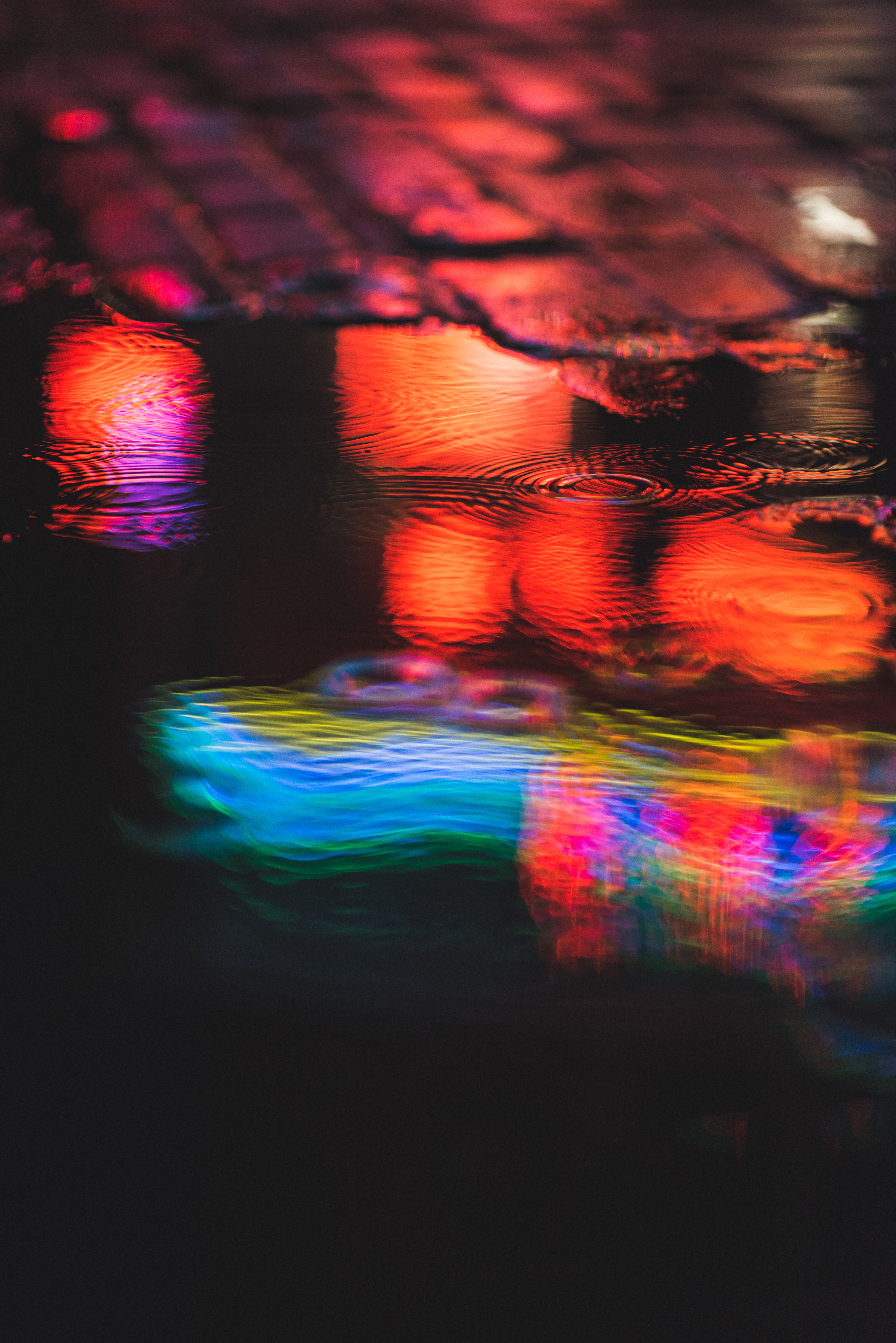 Colorful light reflection on water. Blue, orange, yellow ripples and orbs.