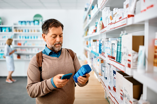Image of a man reading the label on medicine