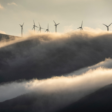 Wind turbines peeking up over clouds