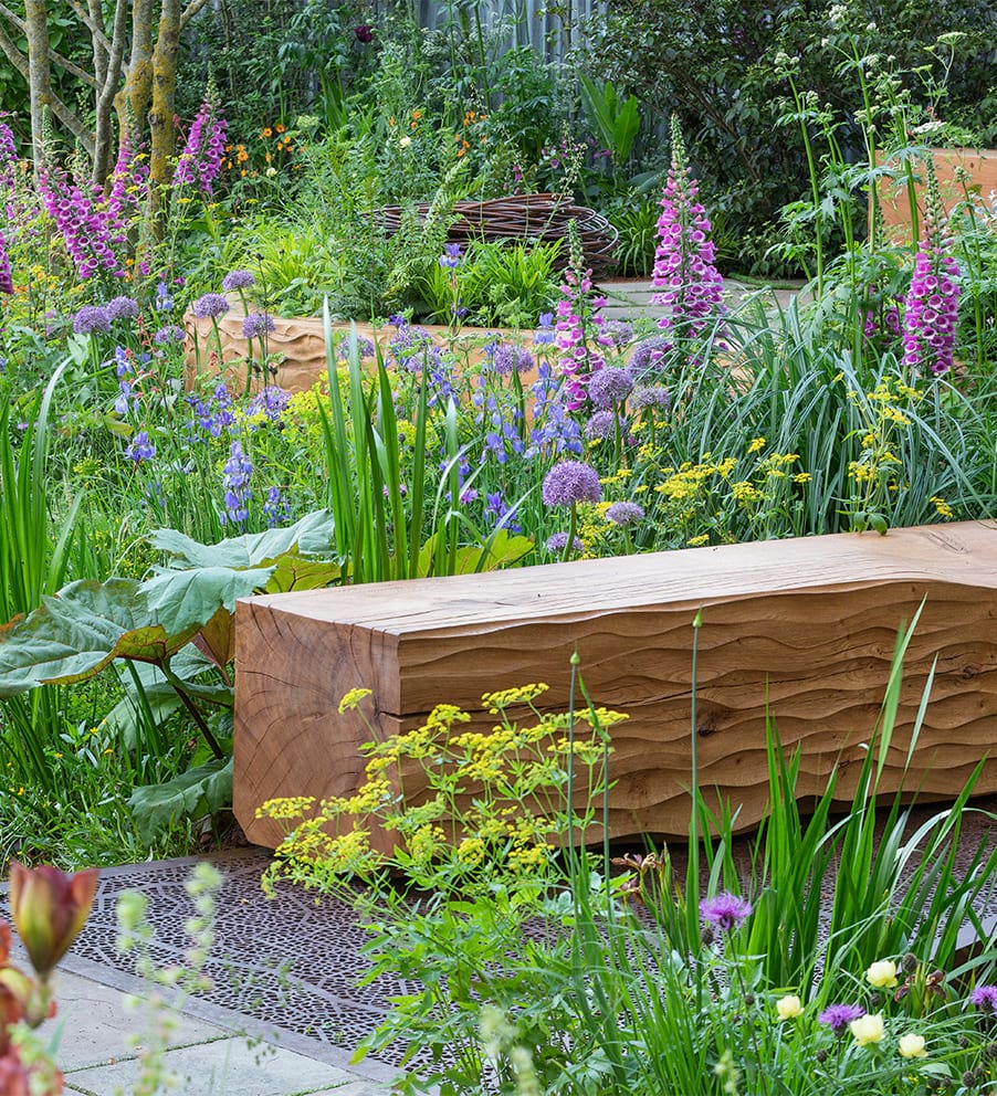 National Trust garden at Chelsea flower show with wooden bench surrounded by wild flowers