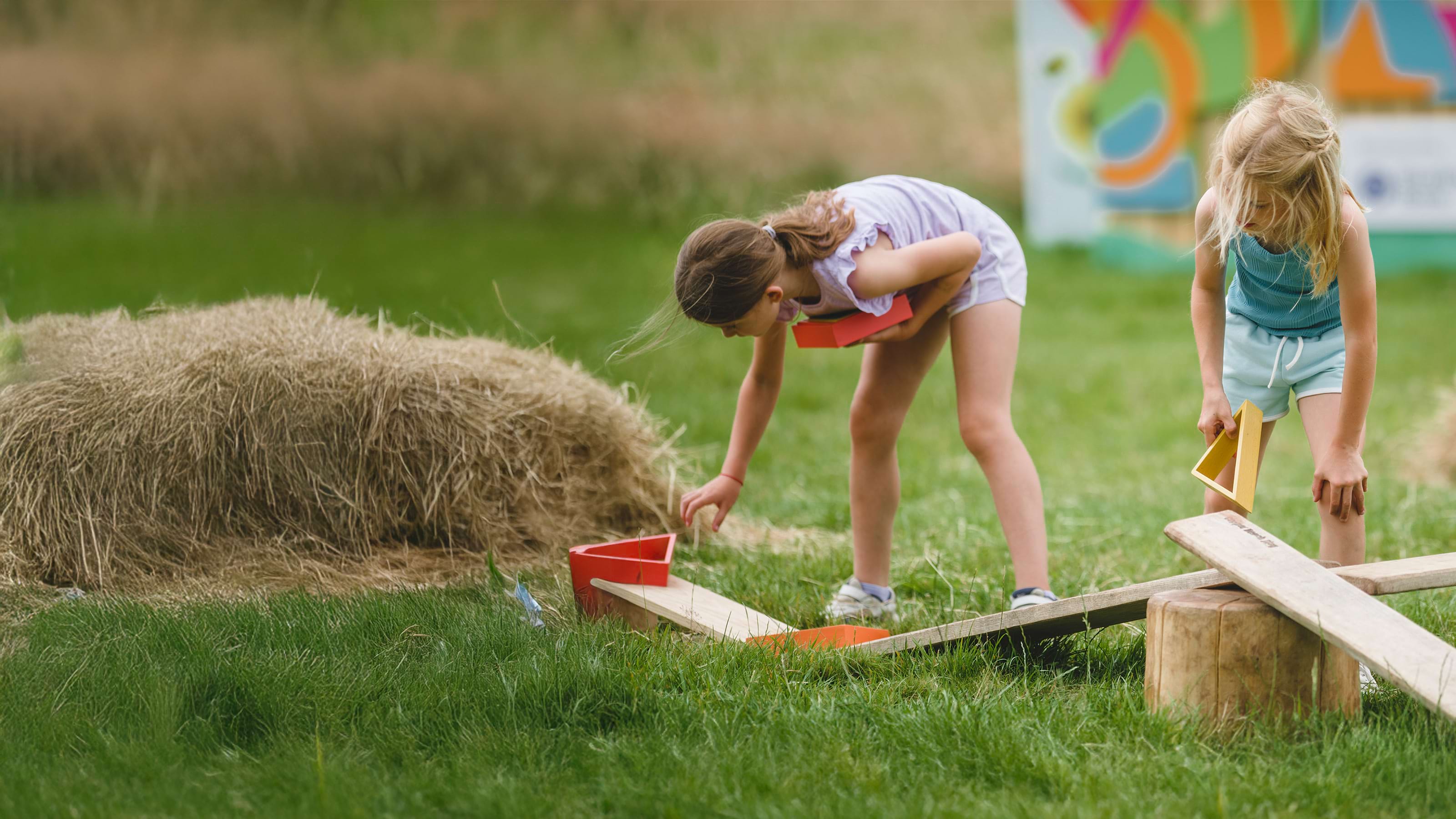 Two children are building a balance course using planks