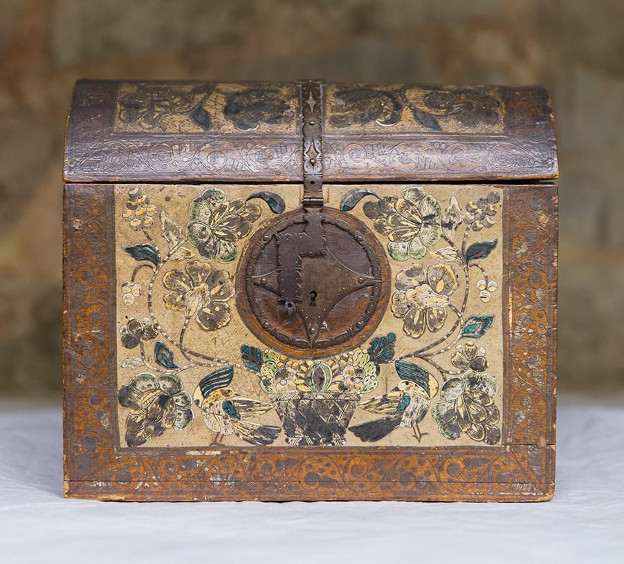 A small wooded casket exhibiting  a complex design of flowers, fruits, and birds