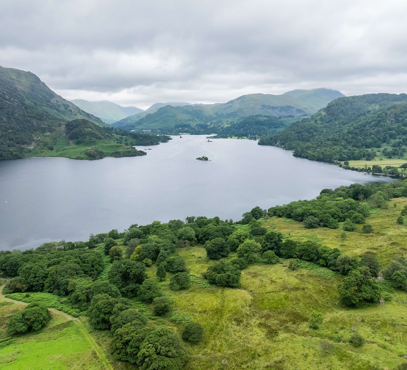 Aerial view over Lake Ullswater in the Lake District and green land previously farmed