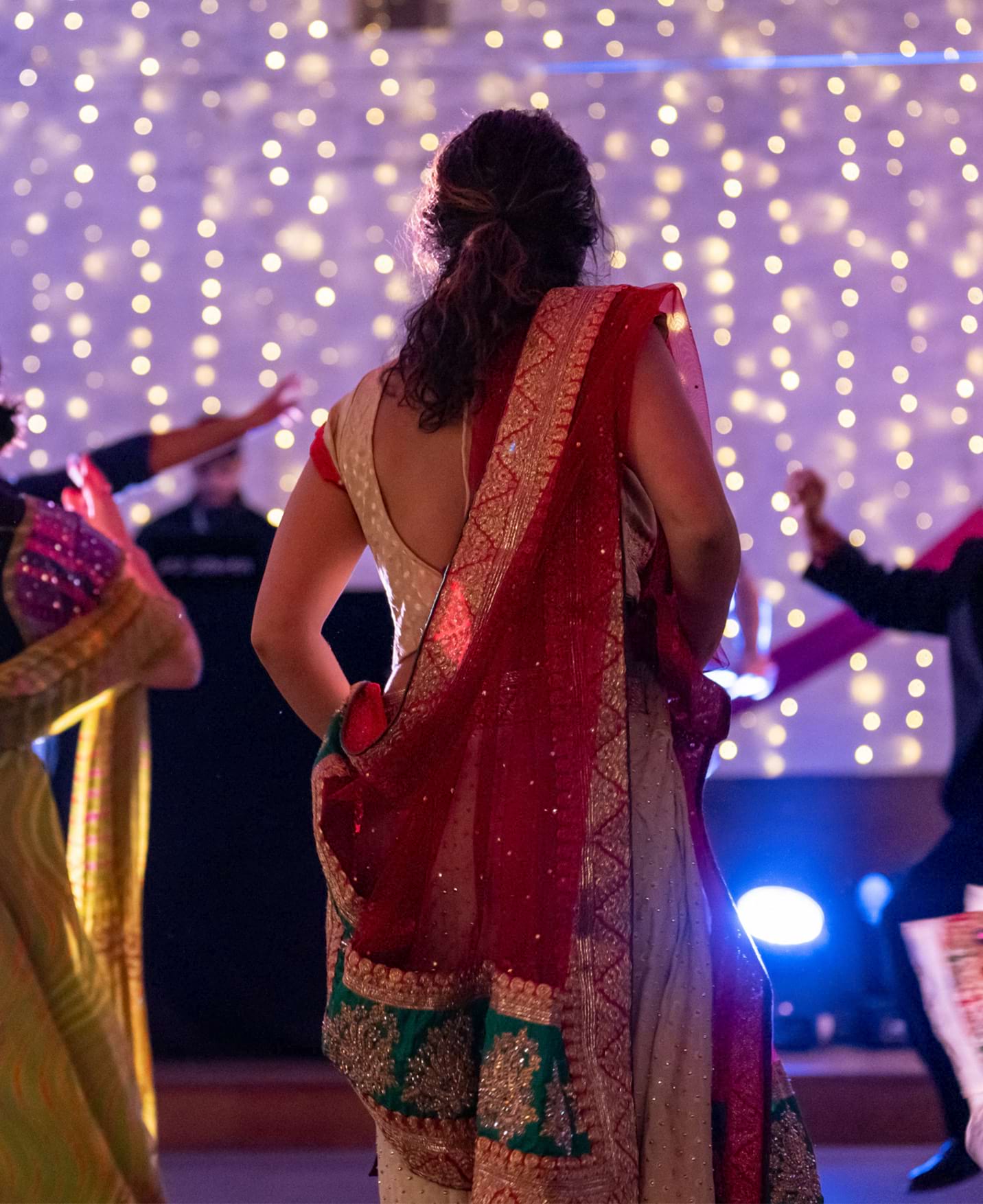 Two people dressed in traditional indian clothing are dancing during Diwali festivities. It is very colourful
