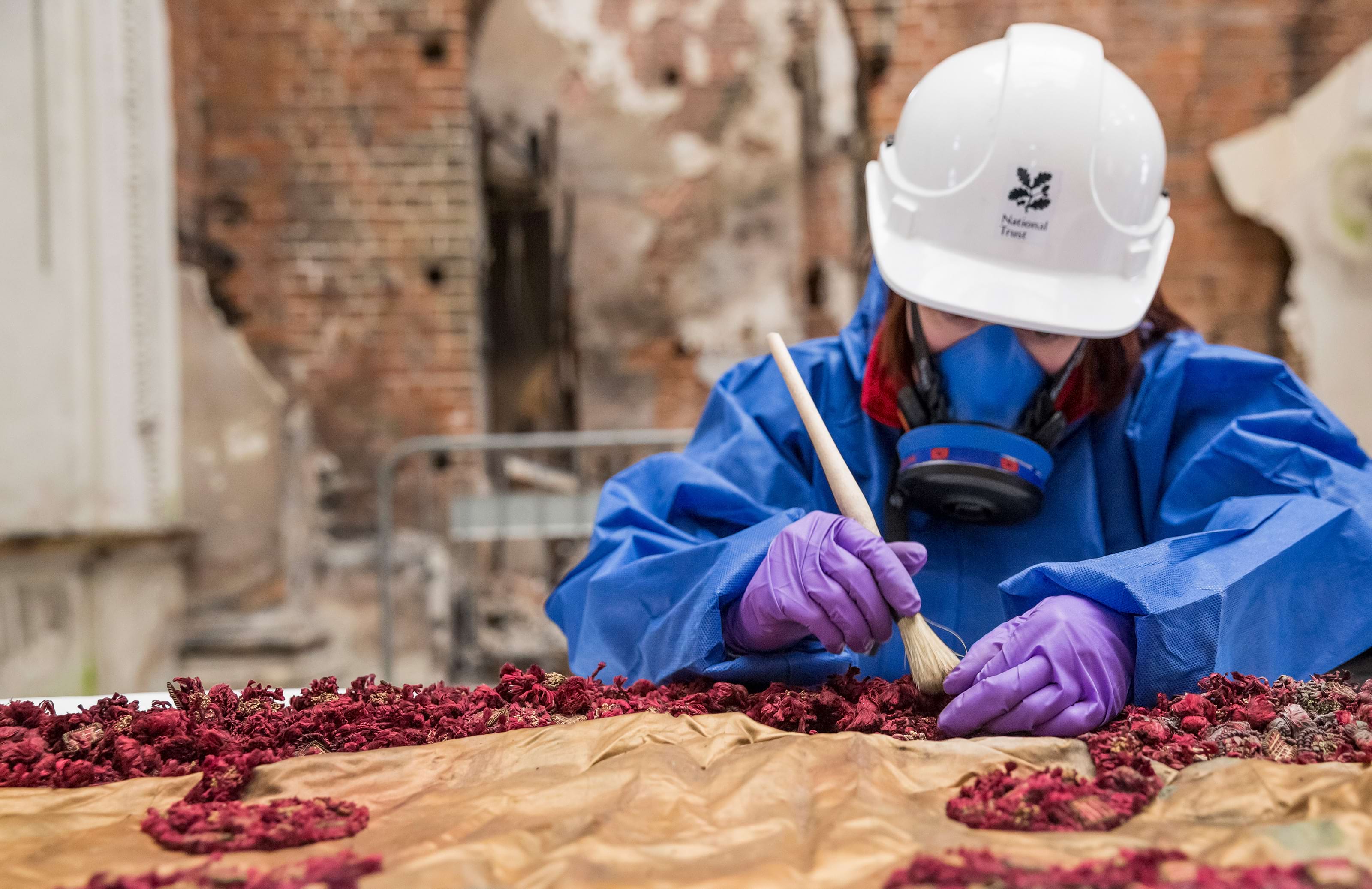 Conservators cleaning the State Bed in the Marble Hall at Clandon Park, Surrey