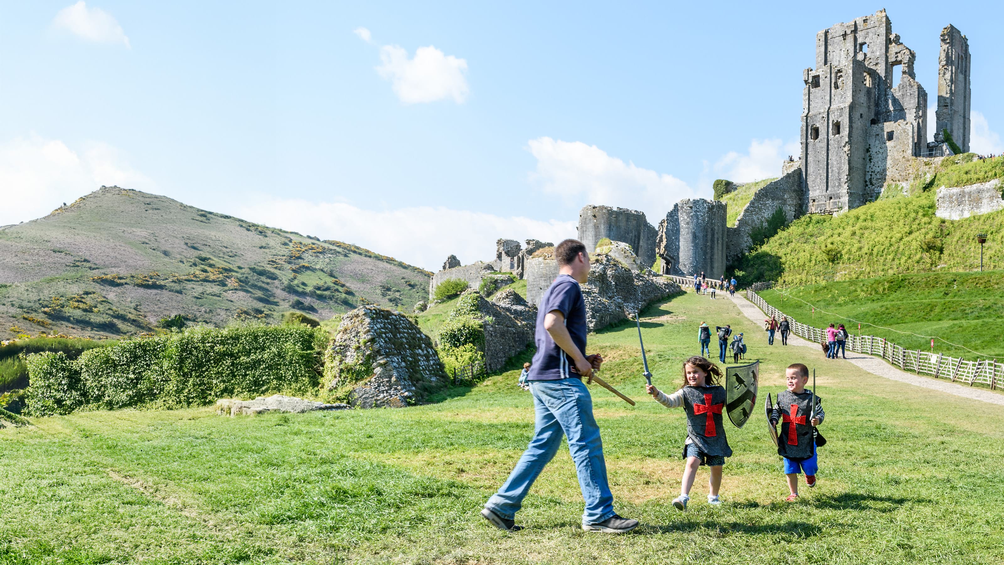 Children dressed up as knights on grass in front of Corfe Castle