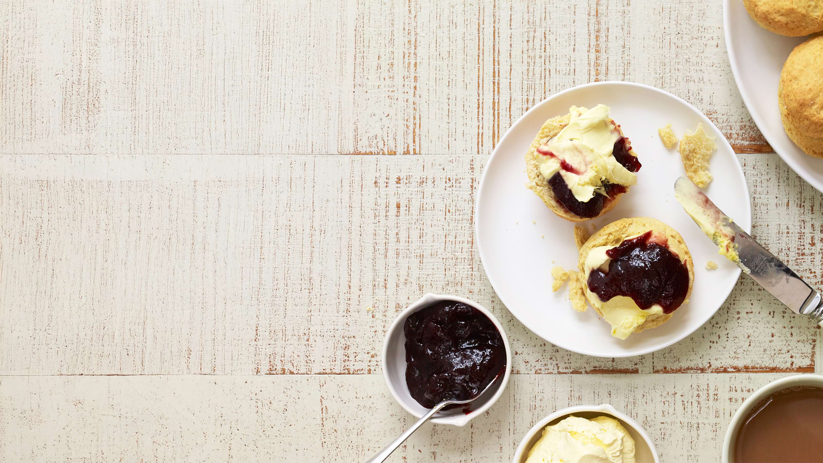 A scone cut in half with jam and cream spread on it