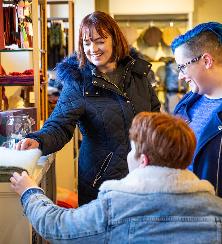 Three ladies looking at items to buy in the National Trust shop 