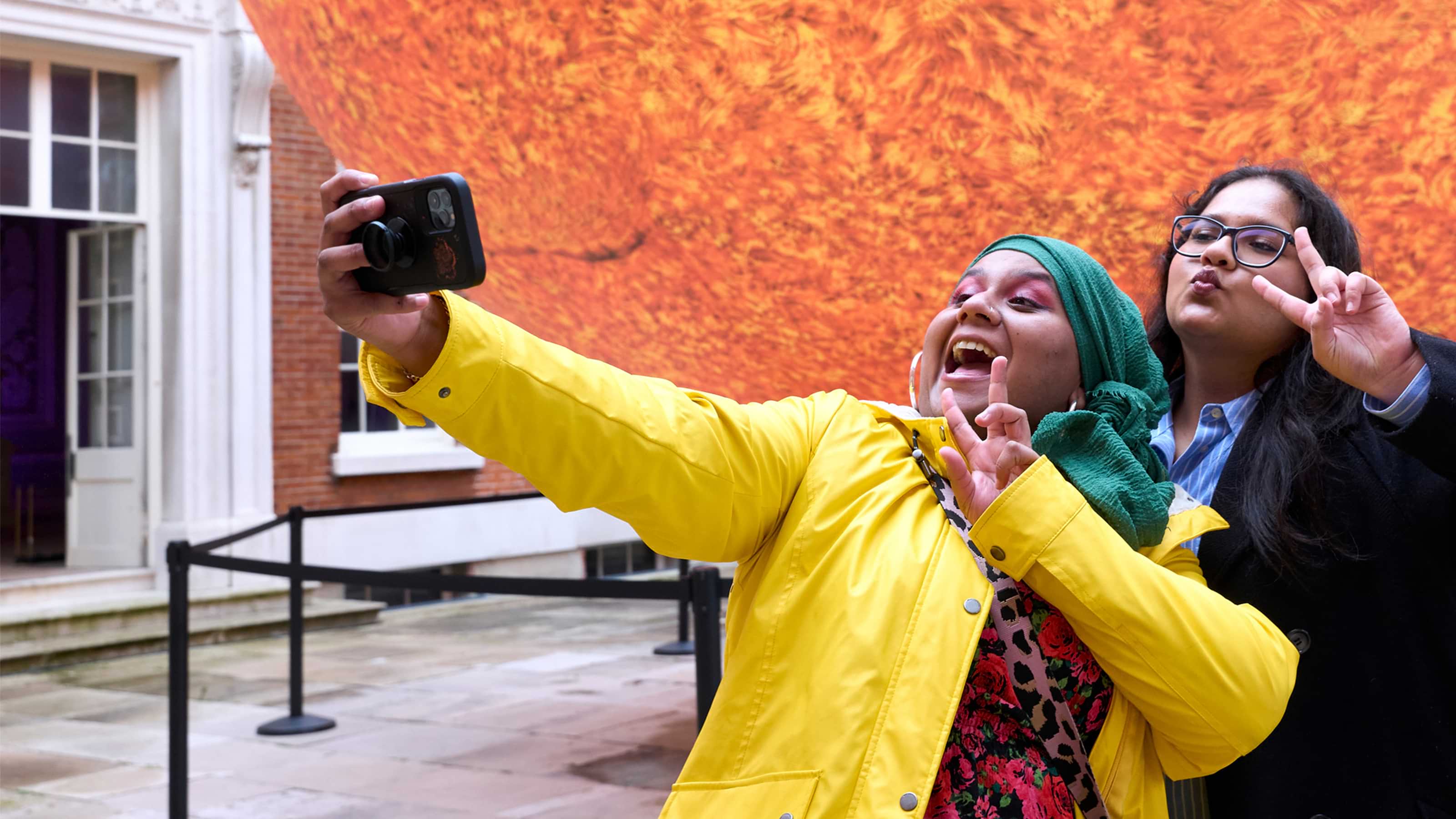 Two ladies in front of the Helios sun installation taking a selfie 