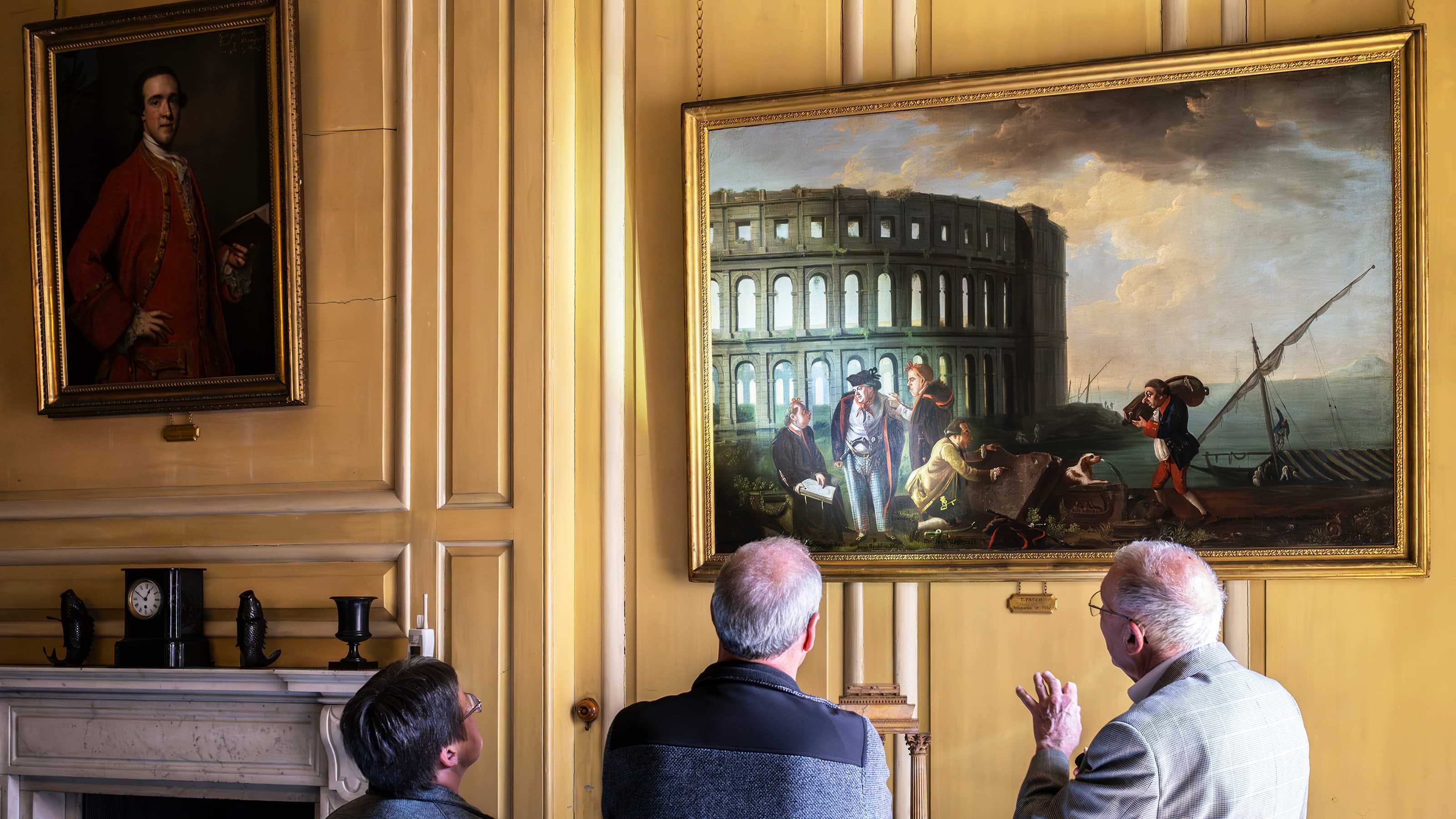 A volunteer discussing a painting on the wall with a visitor 