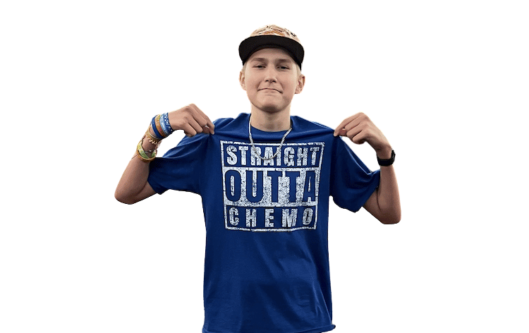 oung patient wearing a 'Straight Outta Chemo' shirt, smiling and holding the sides of the shirt, with a plain background.