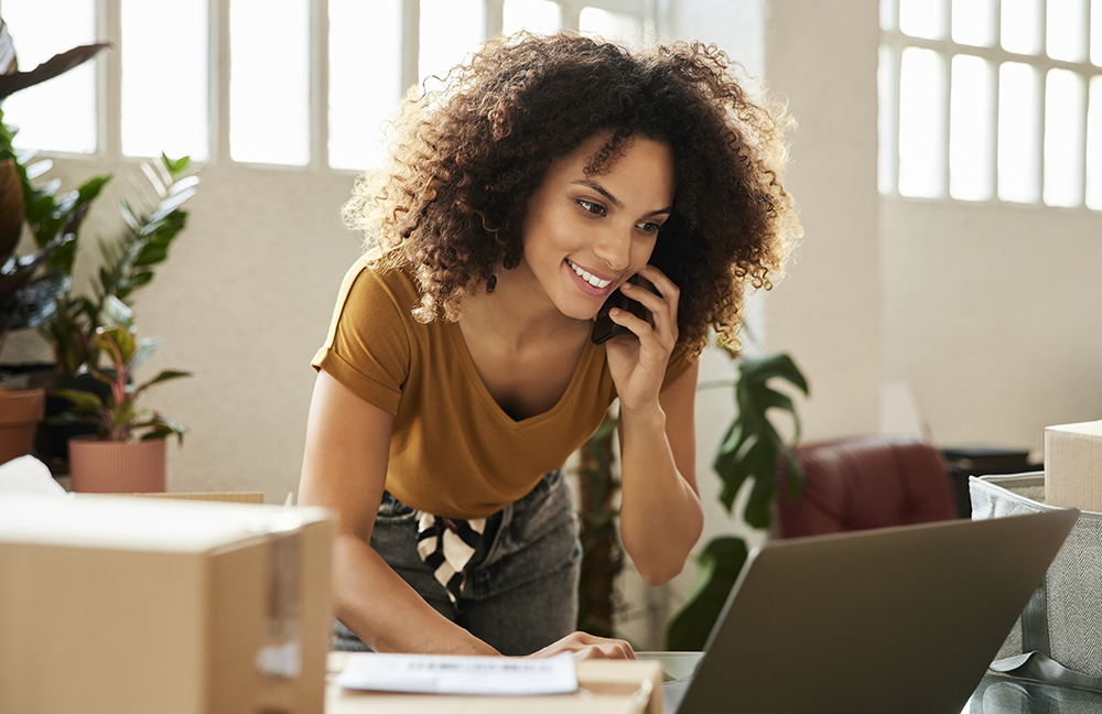 Women on the phone smiling and working on her laptop