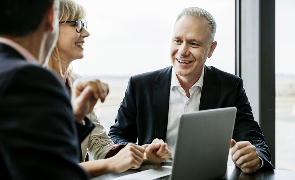 Three employees talking in front of a computer