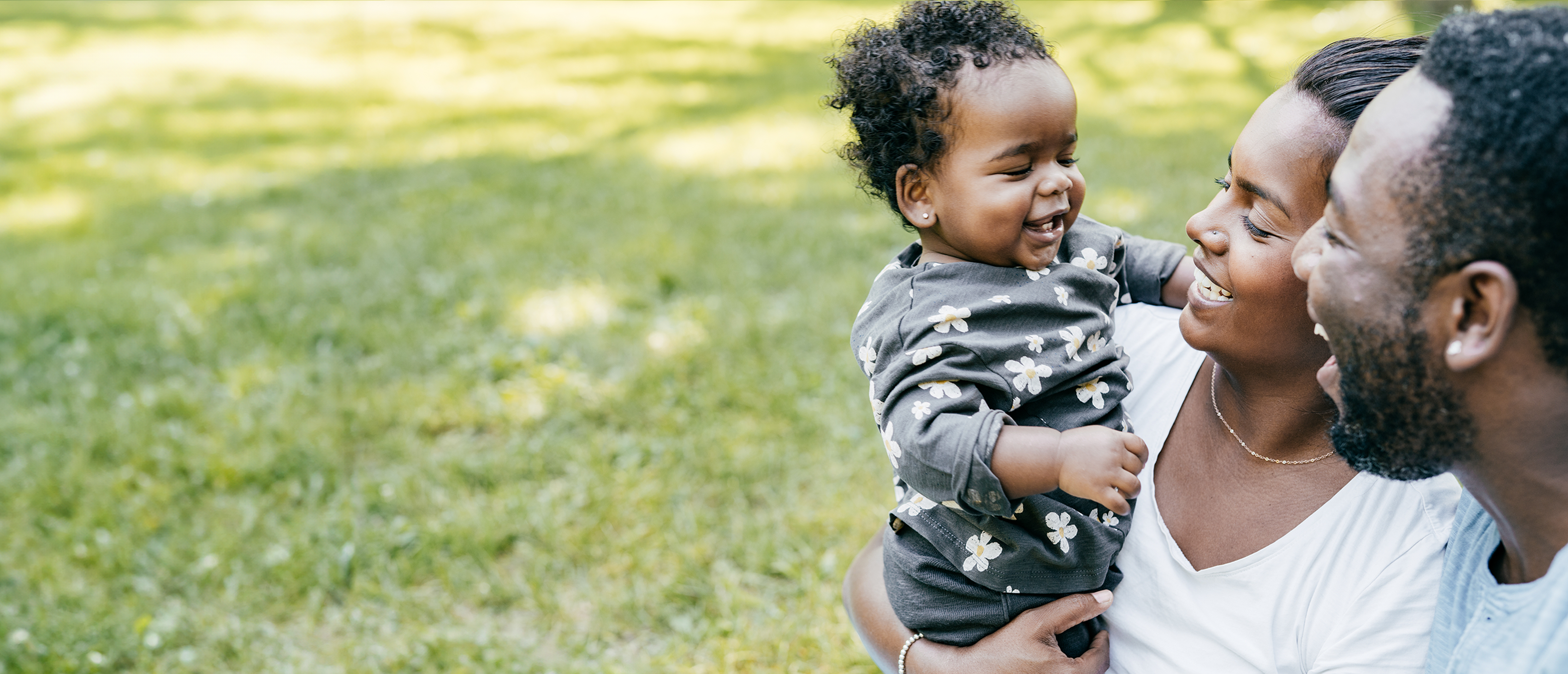 Parents smiling at their baby outside