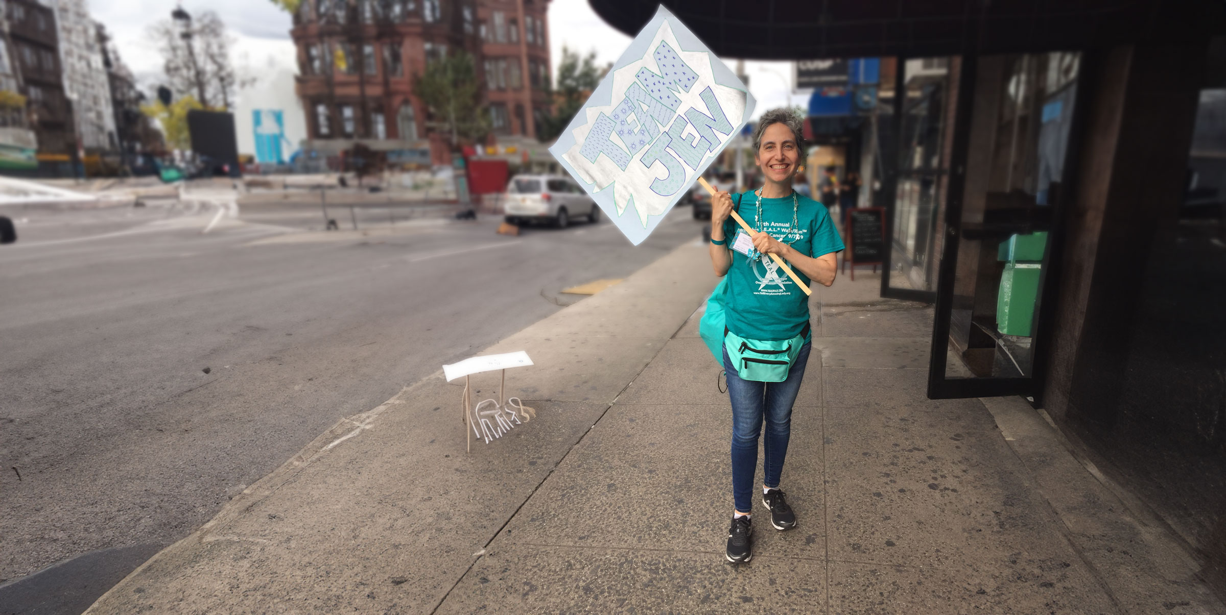 A person is standing on a sidewalk holding a sign that reads 