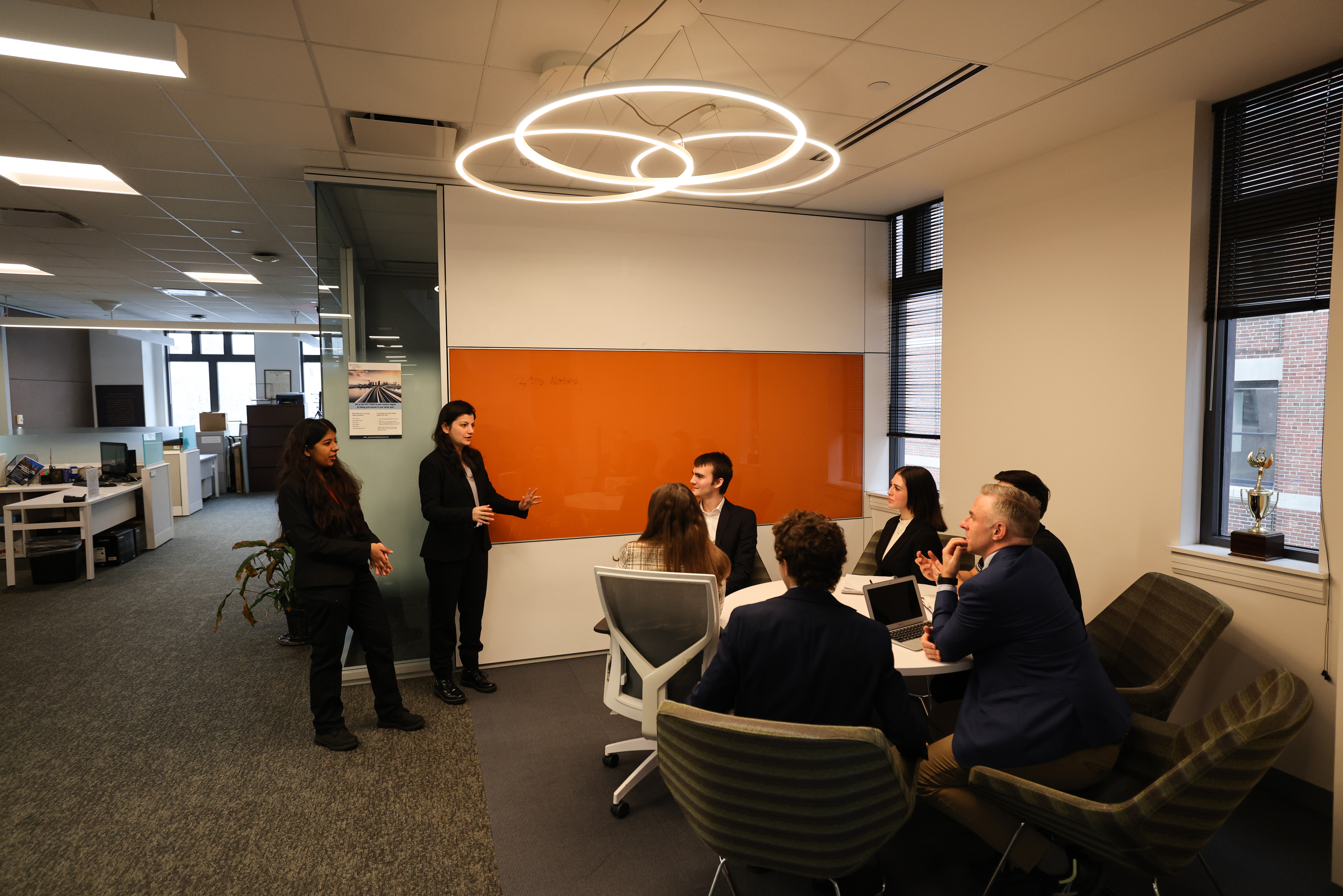 Group of accounting students studying and talking around a circular table in suits.