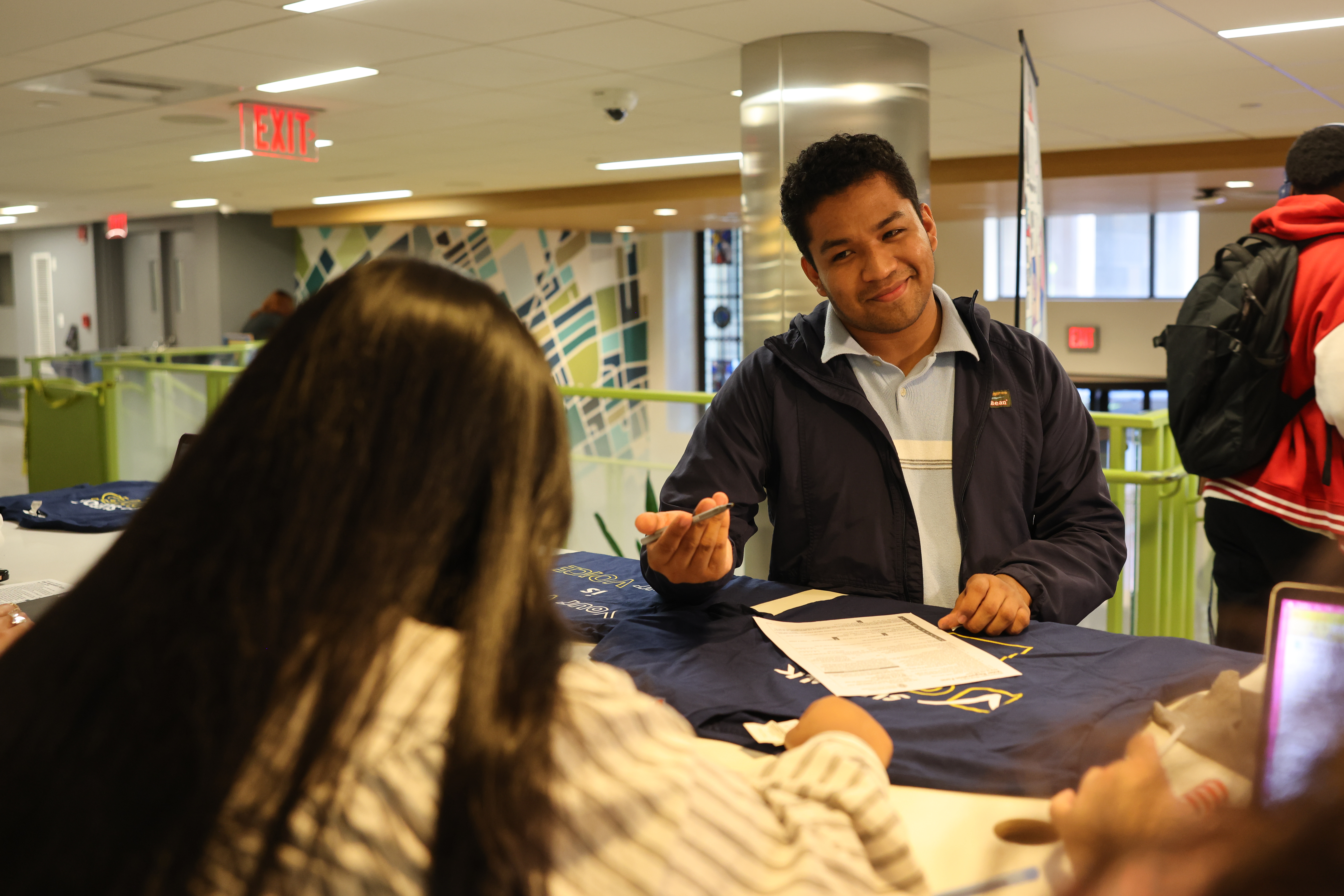 Diverse male student signing up to vote and signing a paper.